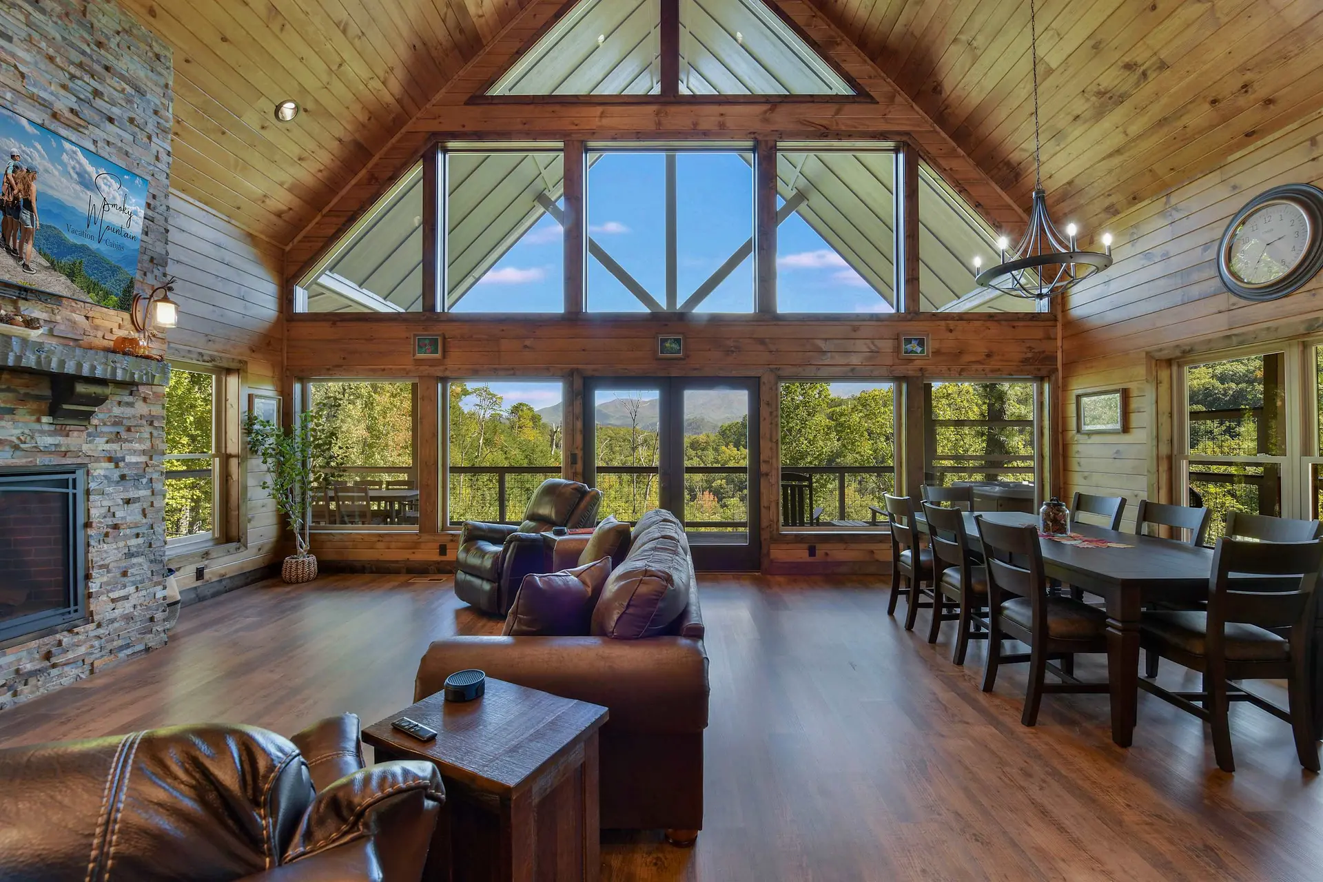 Living room with a fireplace, large windows, leather furniture, and a dining area.