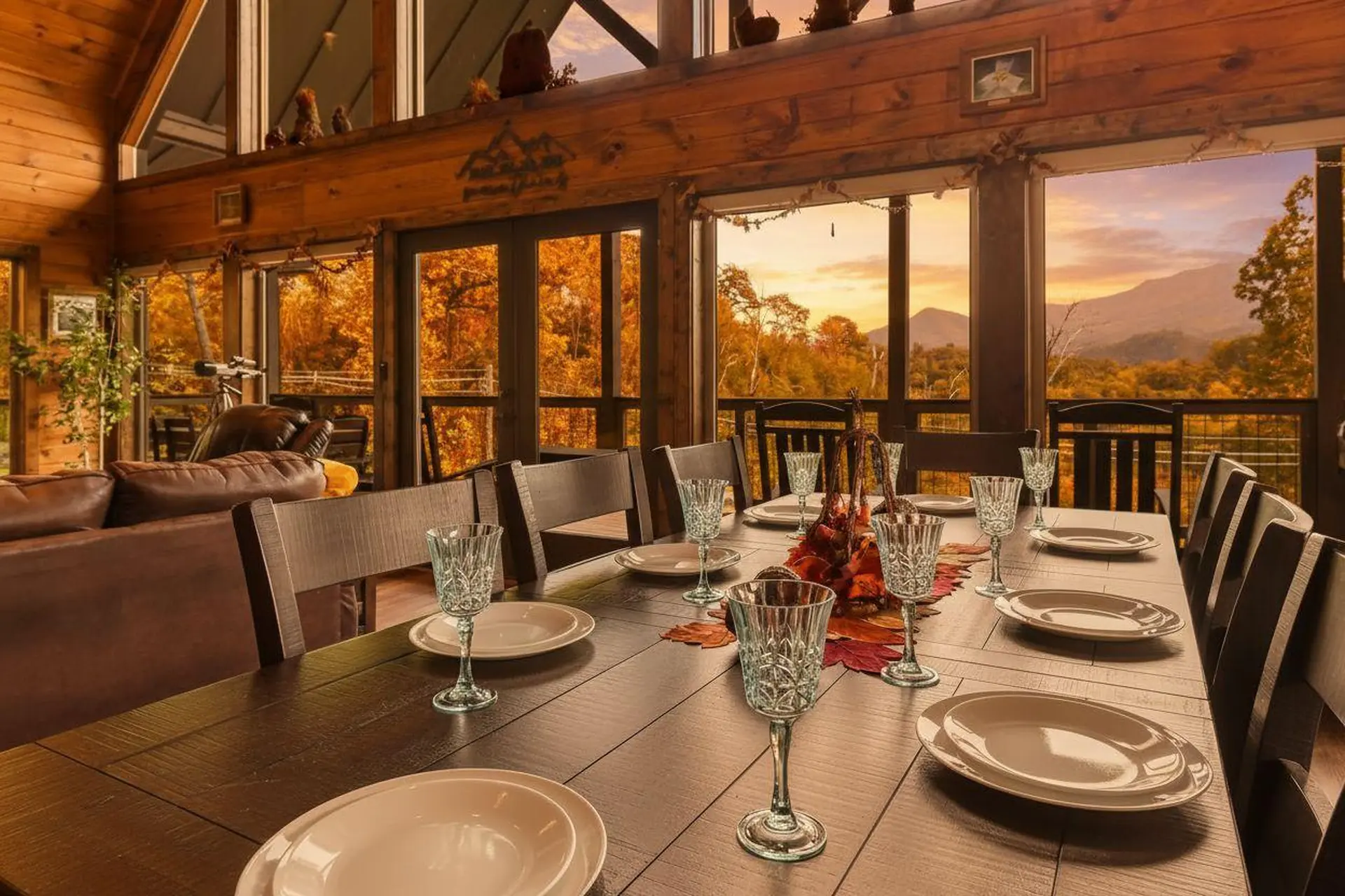 A rustic dining room table set for a feast overlooks a scenic mountain landscape.