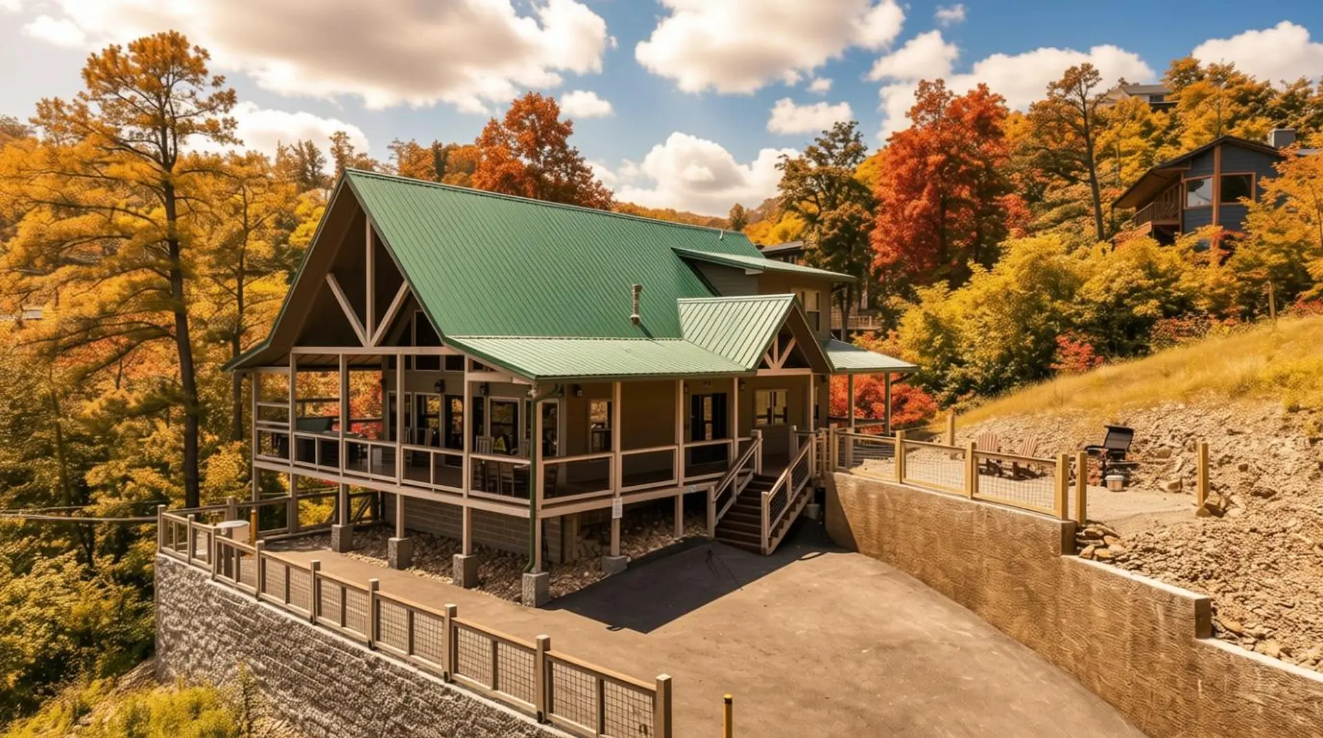 A cabin with a green roof sits on a hill surrounded by autumn foliage.