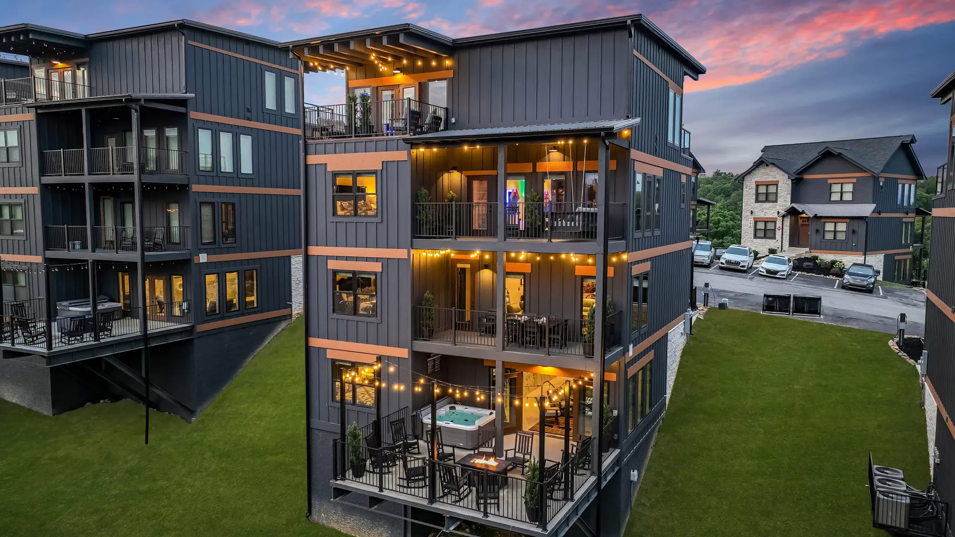 Modern lodge with multiple balconies featuring hot tub and string lights.