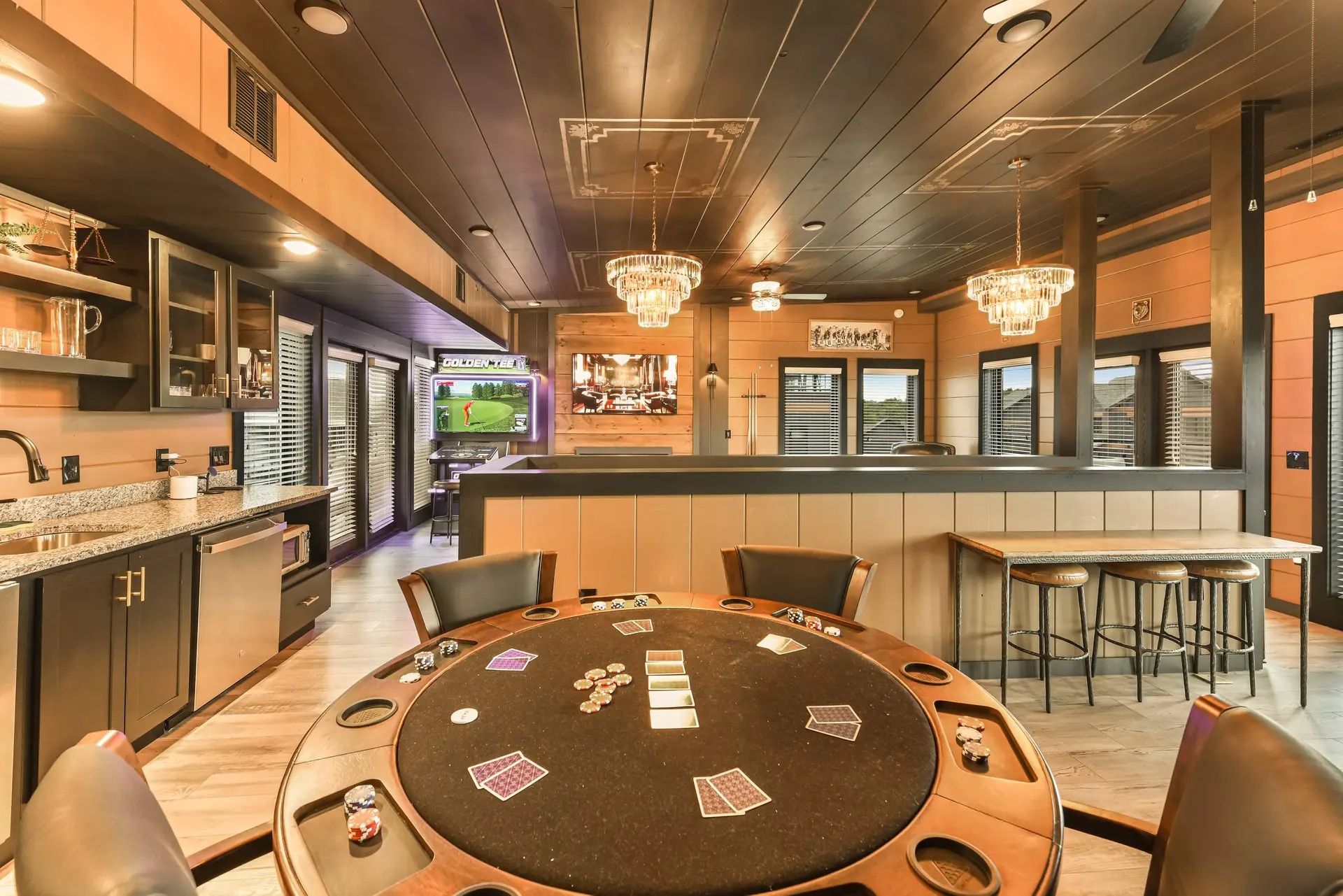 A basement entertainment area with a poker table, arcade game, and bar.