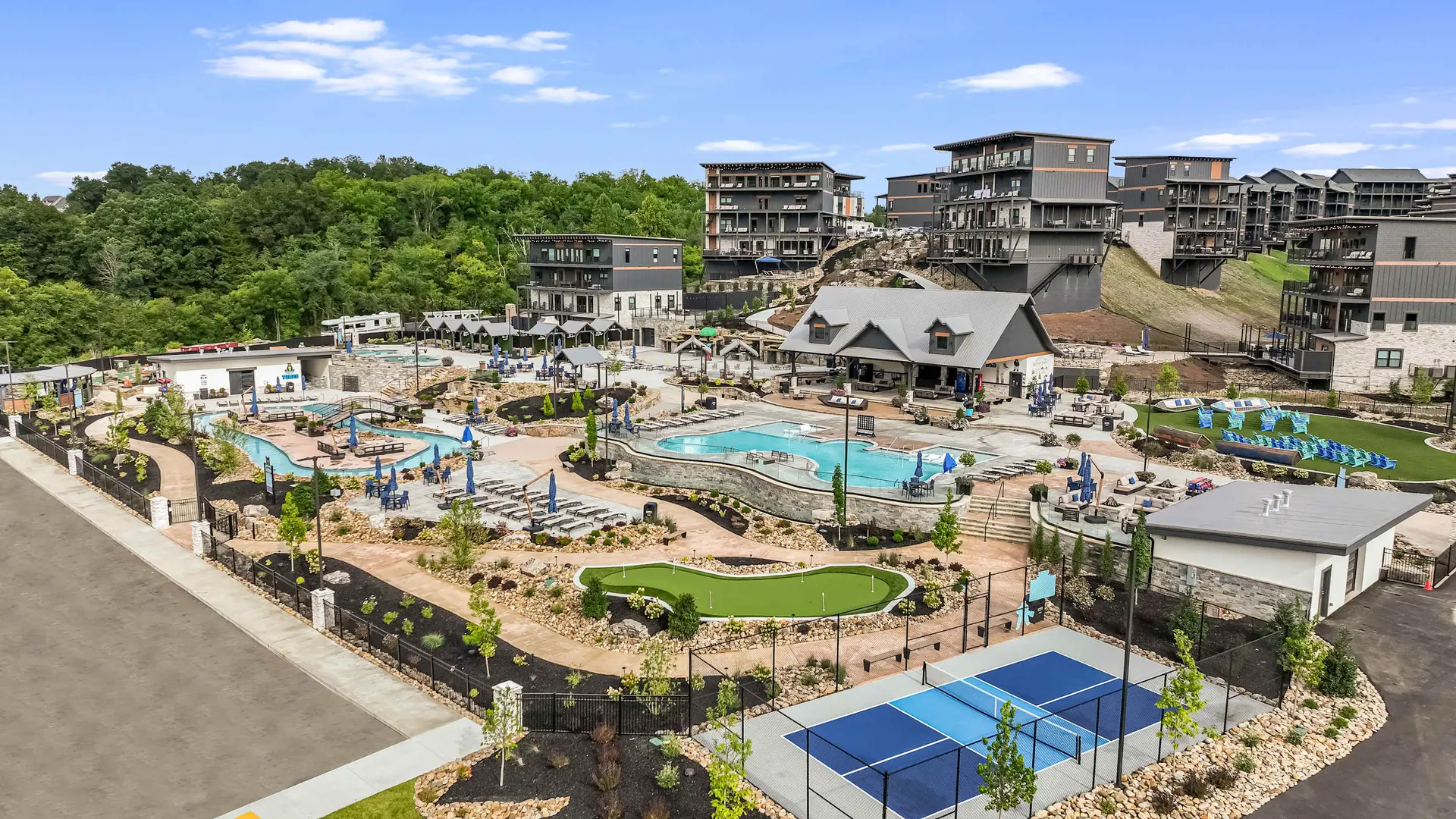 Resort with pools, mini golf, pickleball courts, and modern buildings nestled in trees.