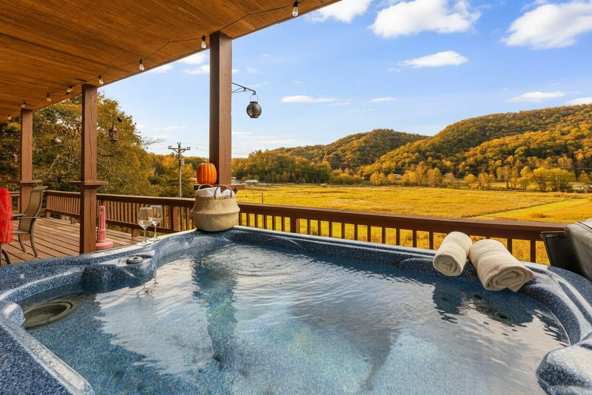 Outdoor hot tub with a scenic view of autumn hills.