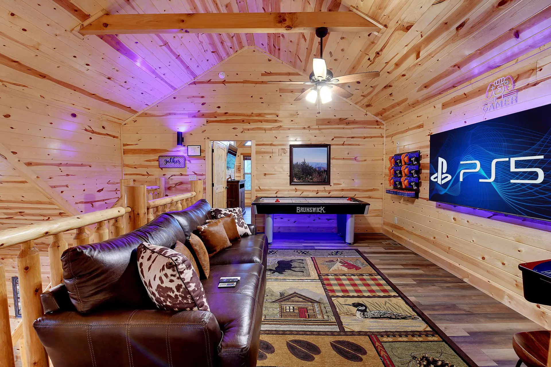 Cozy game room with a brown leather couch, air hockey table, and a large PS5 screen on a wood-panele