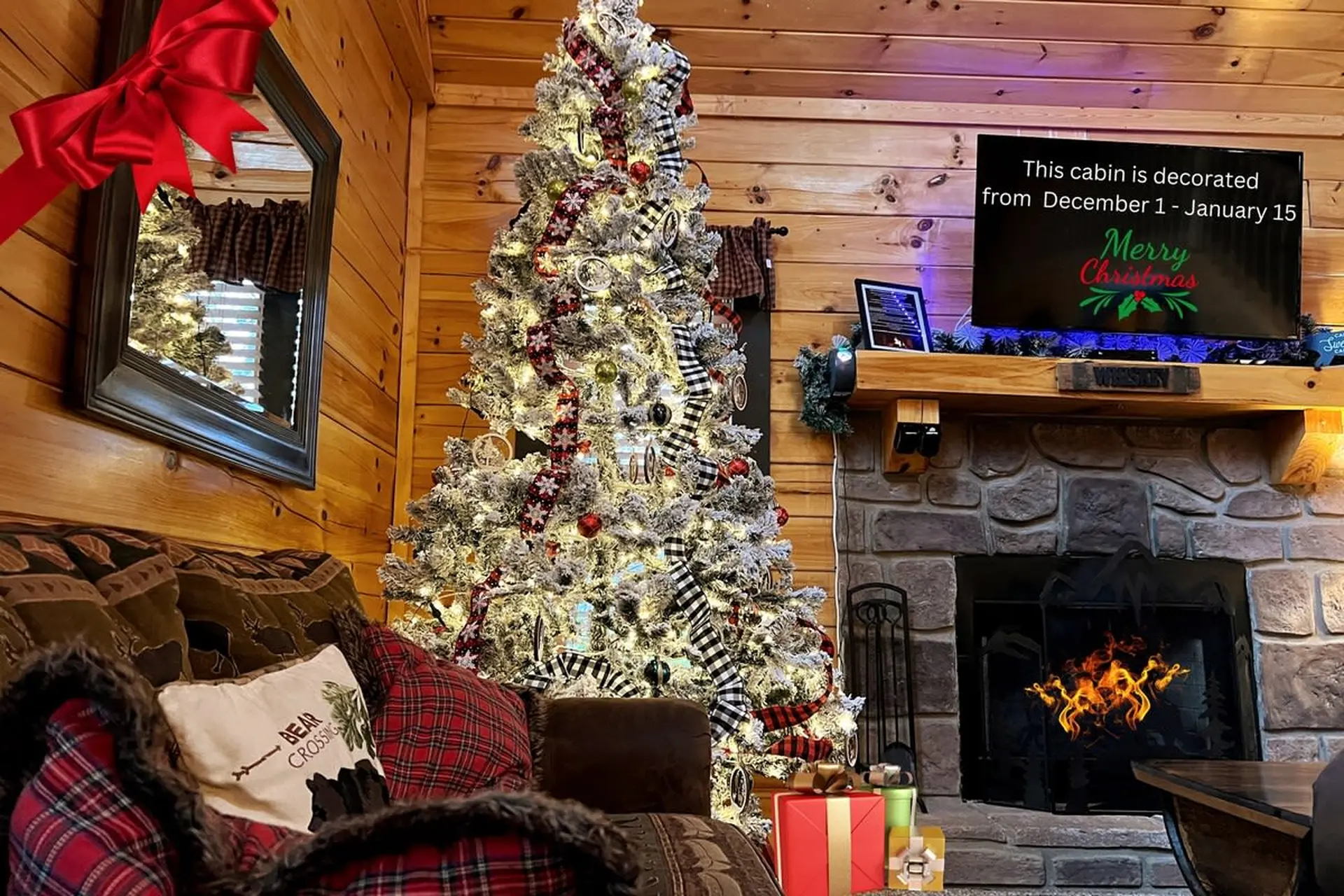 A cozy cabin living room with a decorated Christmas tree and fireplace.