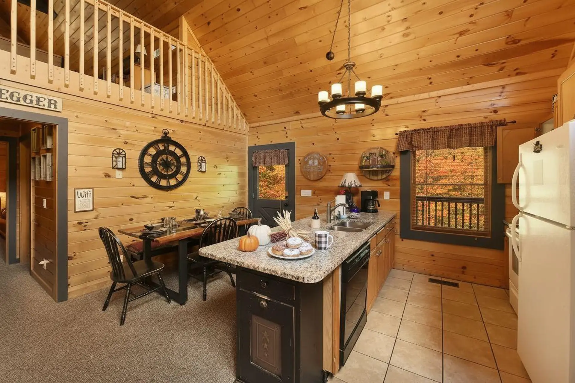 Kitchen with dining table, island, and refrigerator in a log cabin.