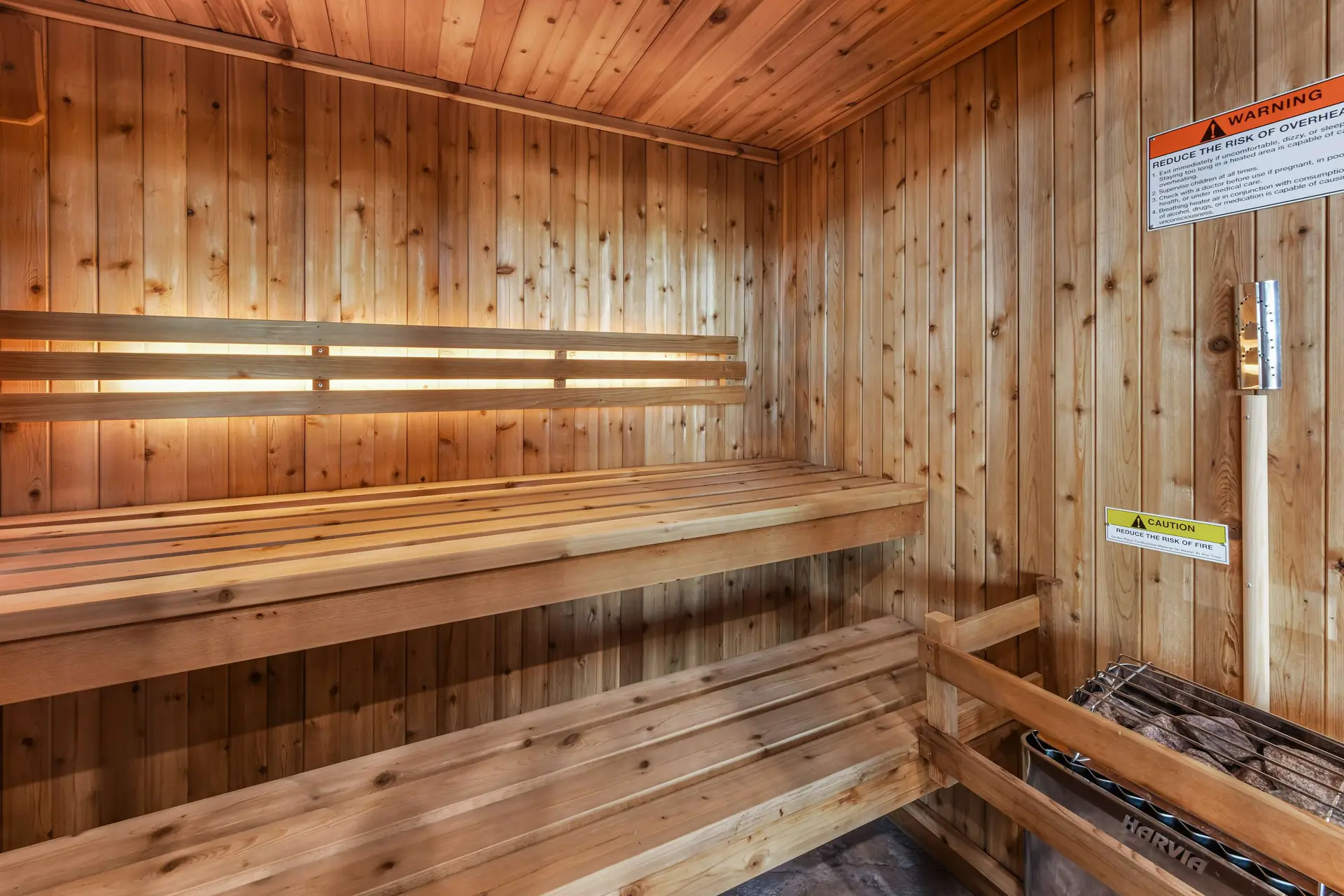 Wooden sauna with benches and a heater.