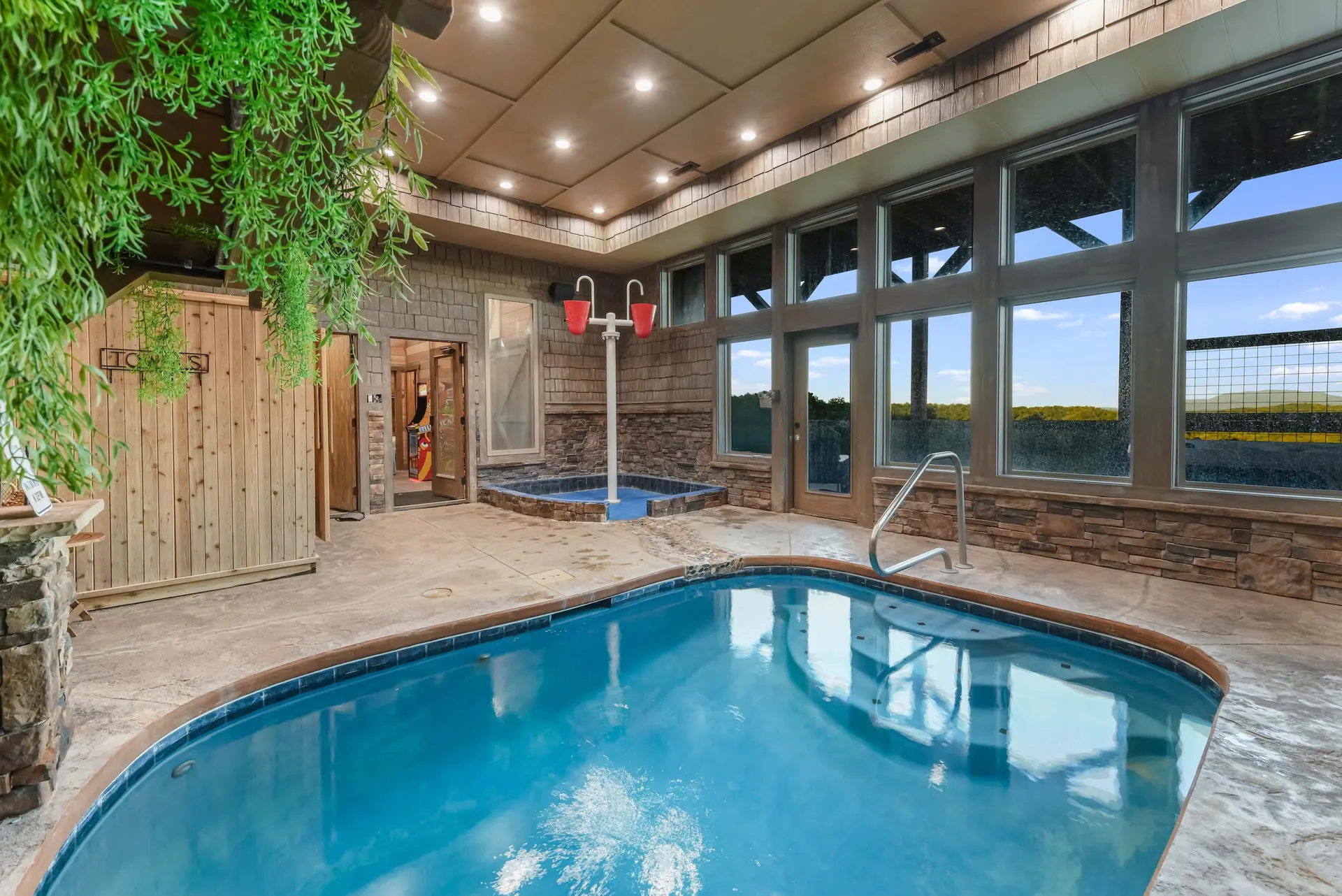 Indoor pool and hot tub area with large windows overlooking a scenic landscape.