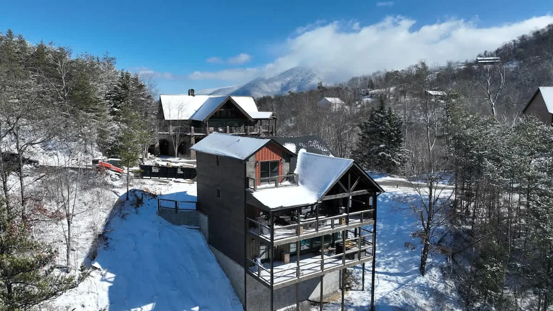 A mountain view with snow-covered houses and trees under a blue sky.