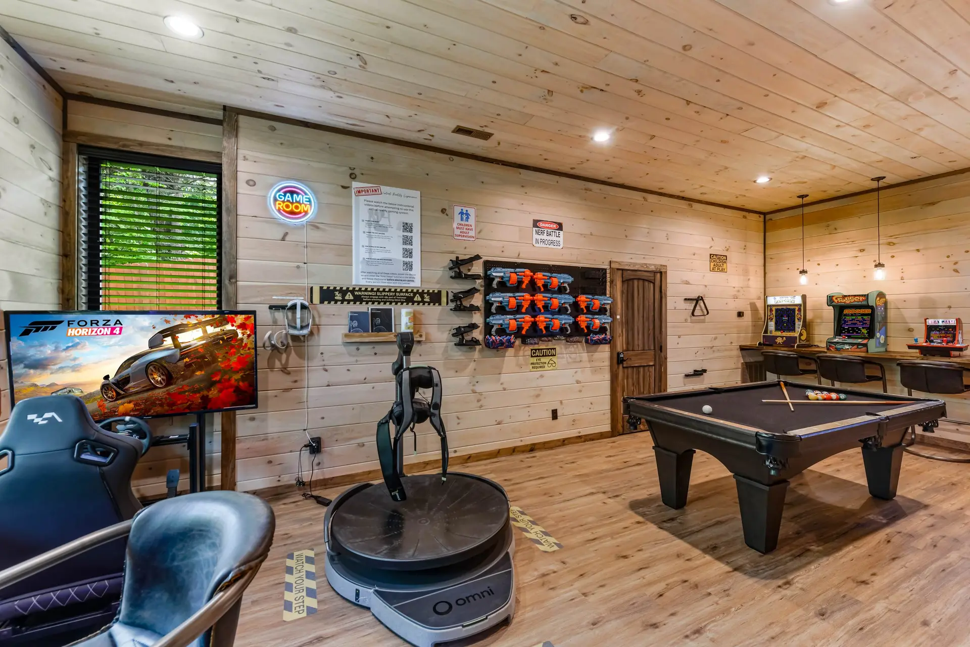 This game room has arcade games, a pool table, and a virtual reality setup.