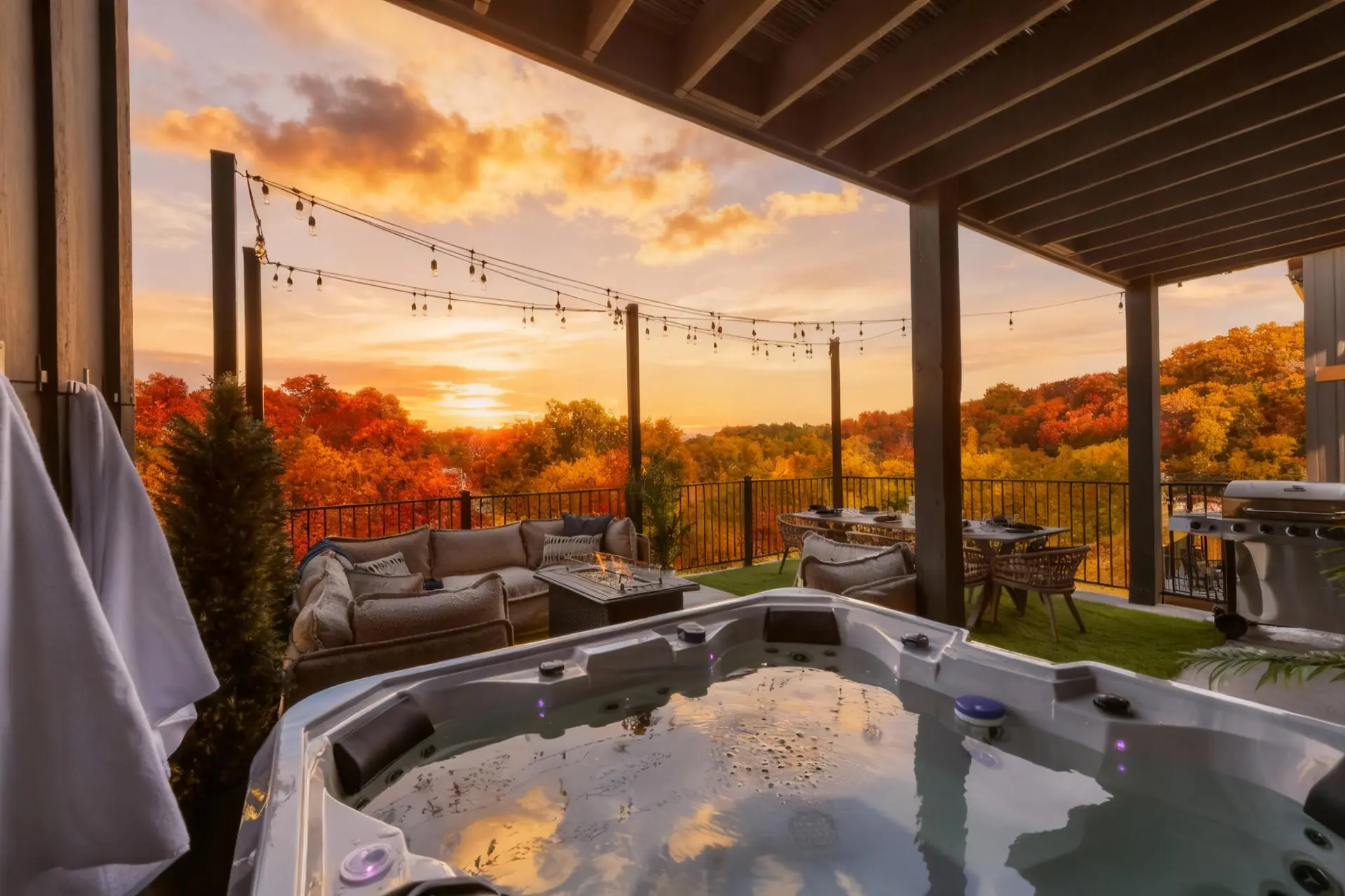 Luxury hot tub on a deck overlooking autumn foliage at sunset.