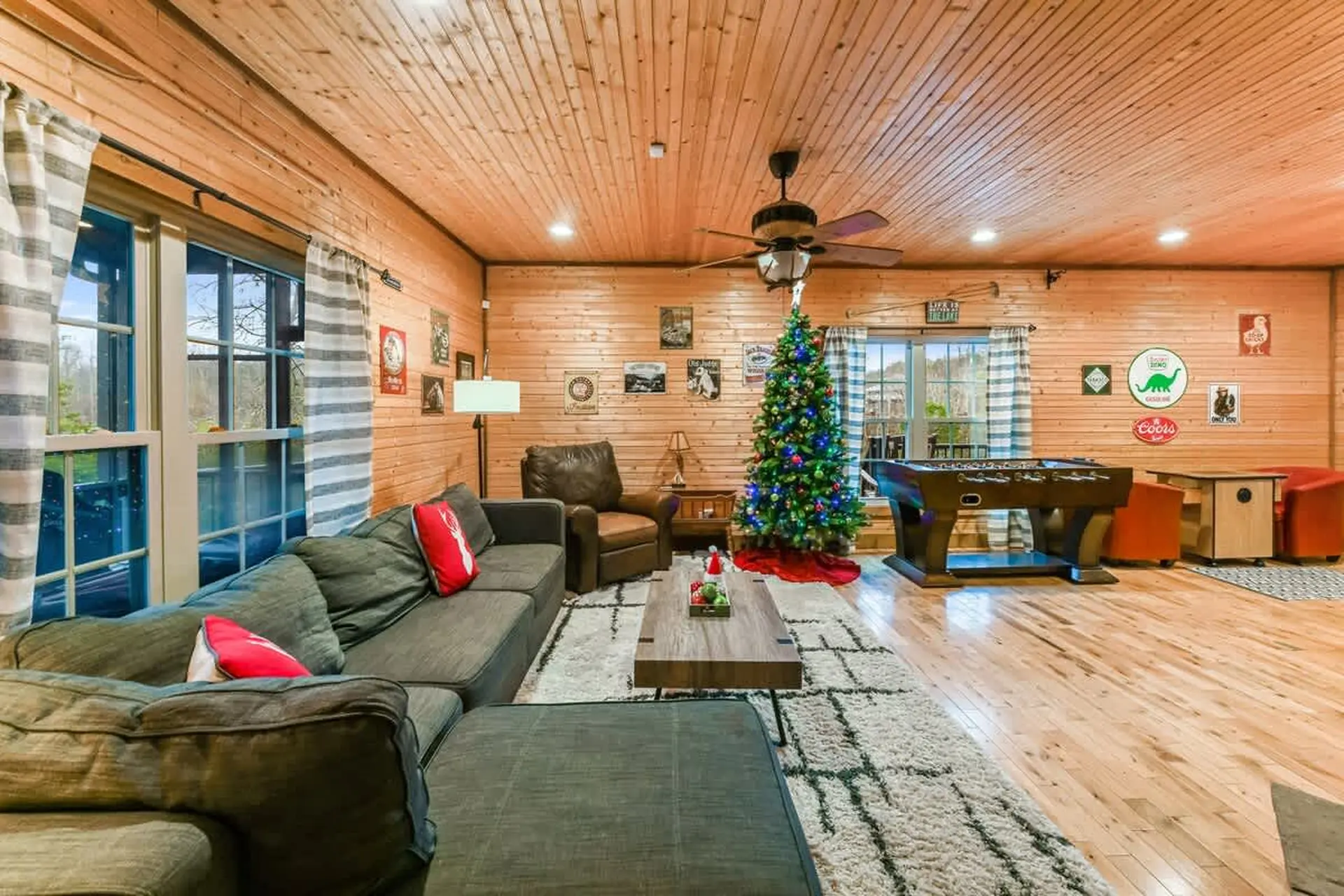 Cozy living room with Christmas tree, foosball table, and rustic wood accents.