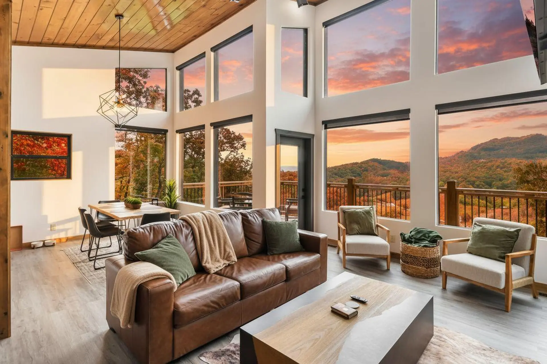Living room with large windows overlooking a mountain view during sunset.