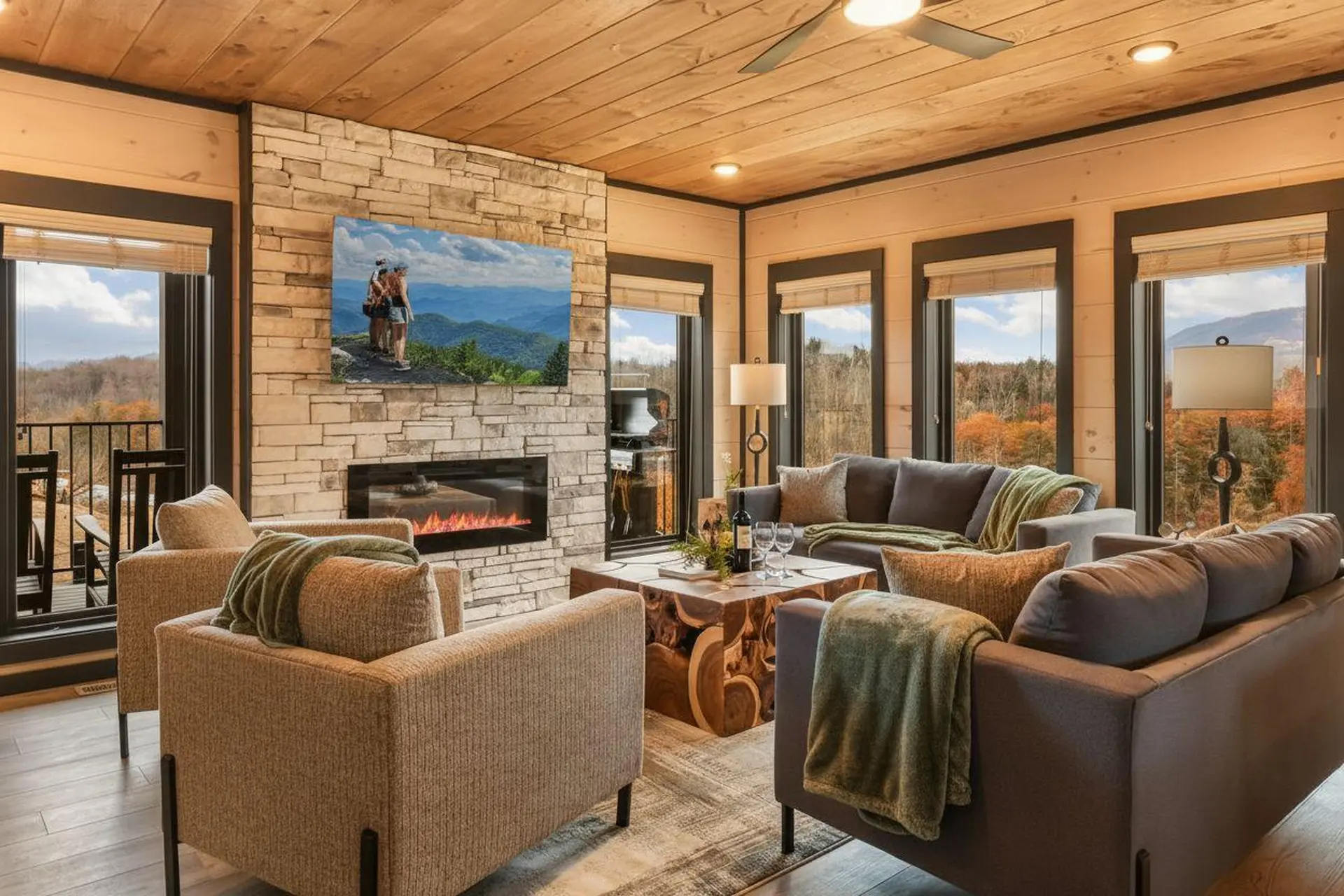 Cozy living room with fireplace, couches, and view of autumn foliage.