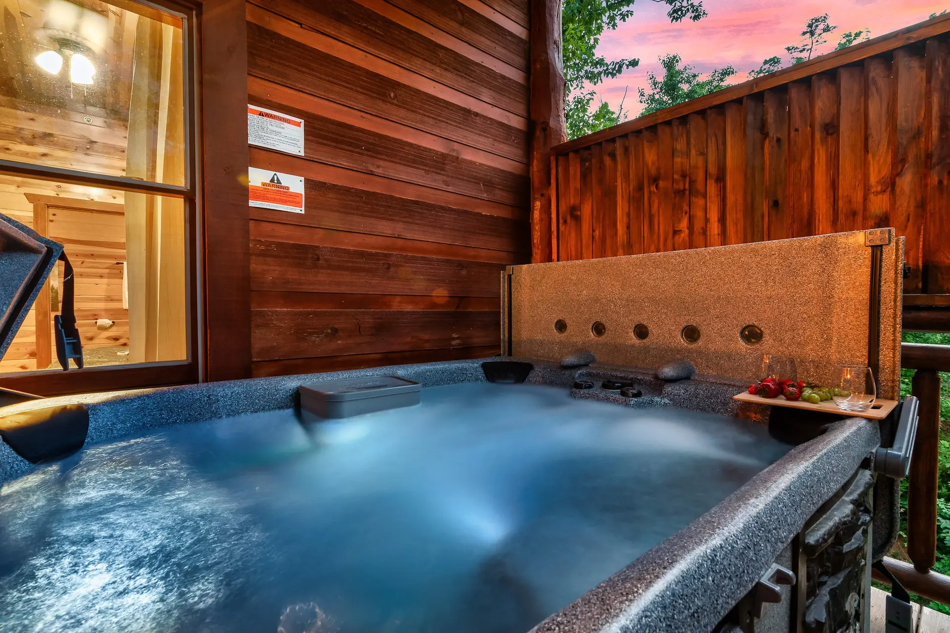 A bubbling hot tub sits on a wooden deck under a sunset sky.
