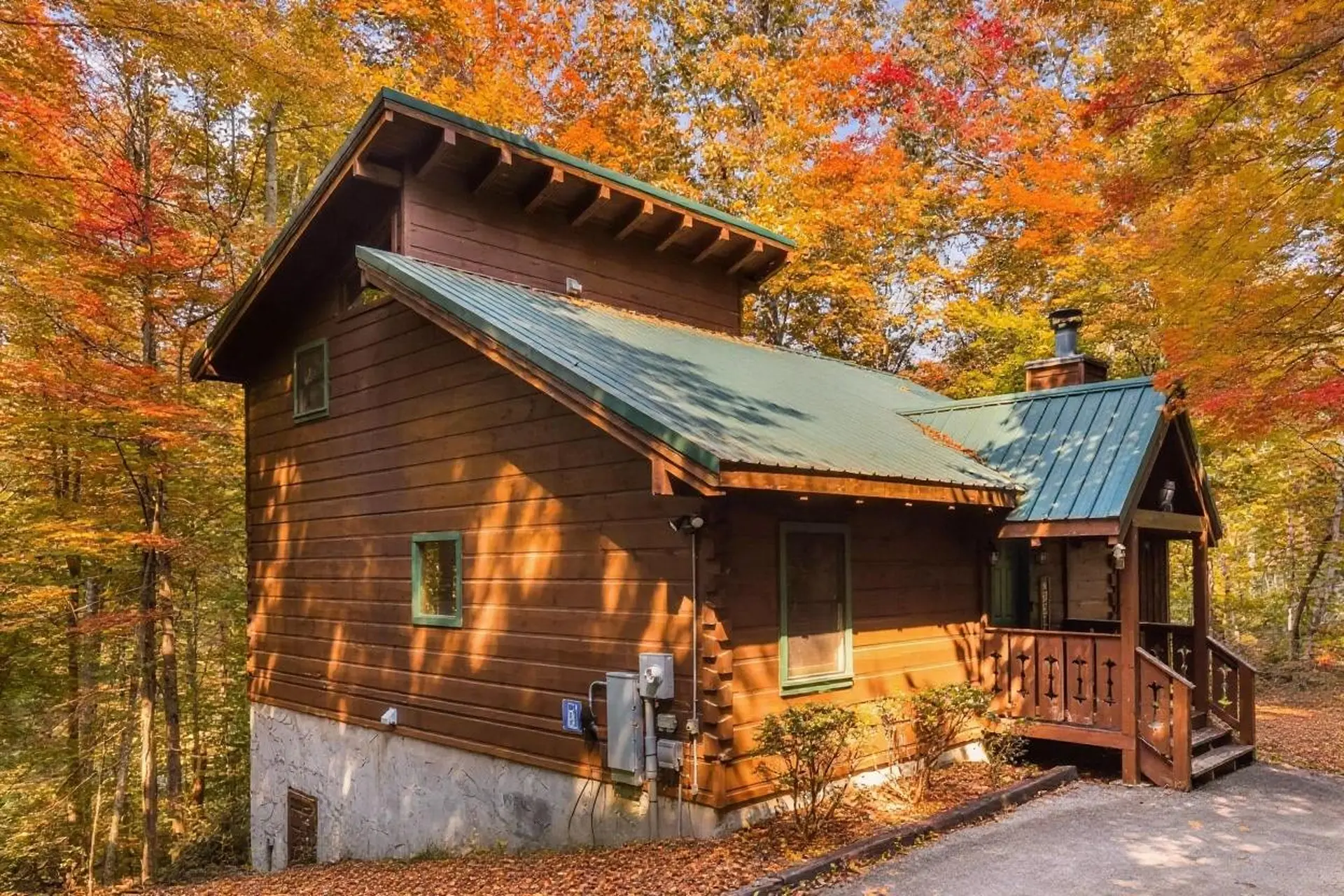 A wooden cabin in a forest during autumn with colorful foliage.