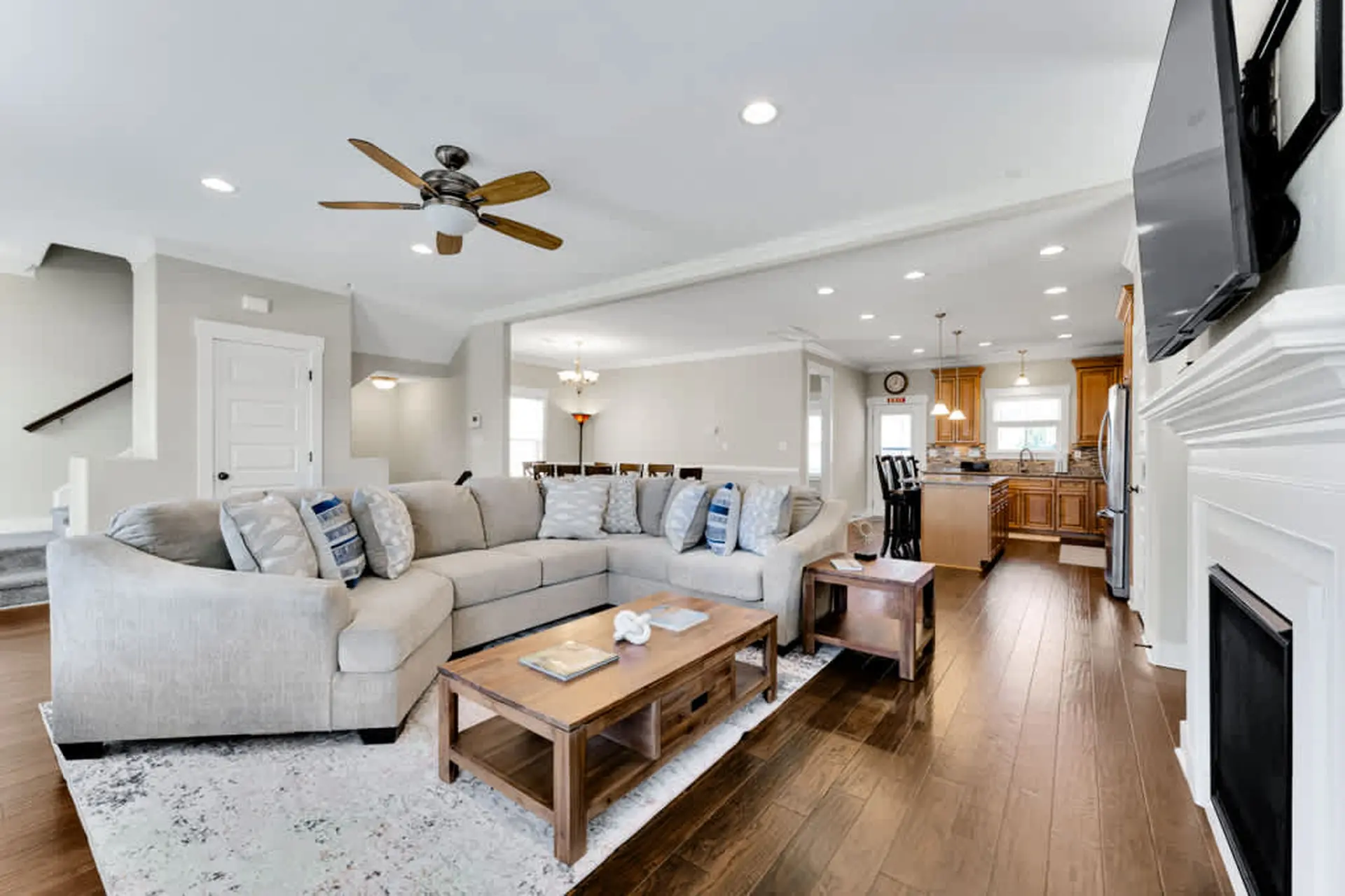 A spacious open-concept living room with a sectional sofa, coffee table, and a kitchen visible.