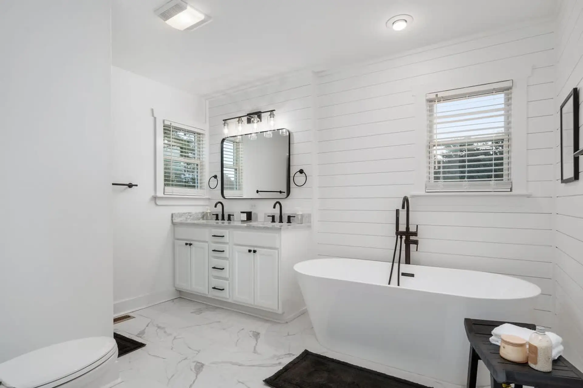 Modern white bathroom with freestanding tub and double vanity.