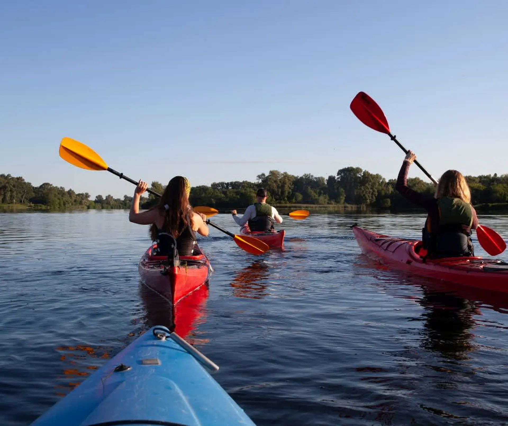 People kayaking on a lake during sunset.