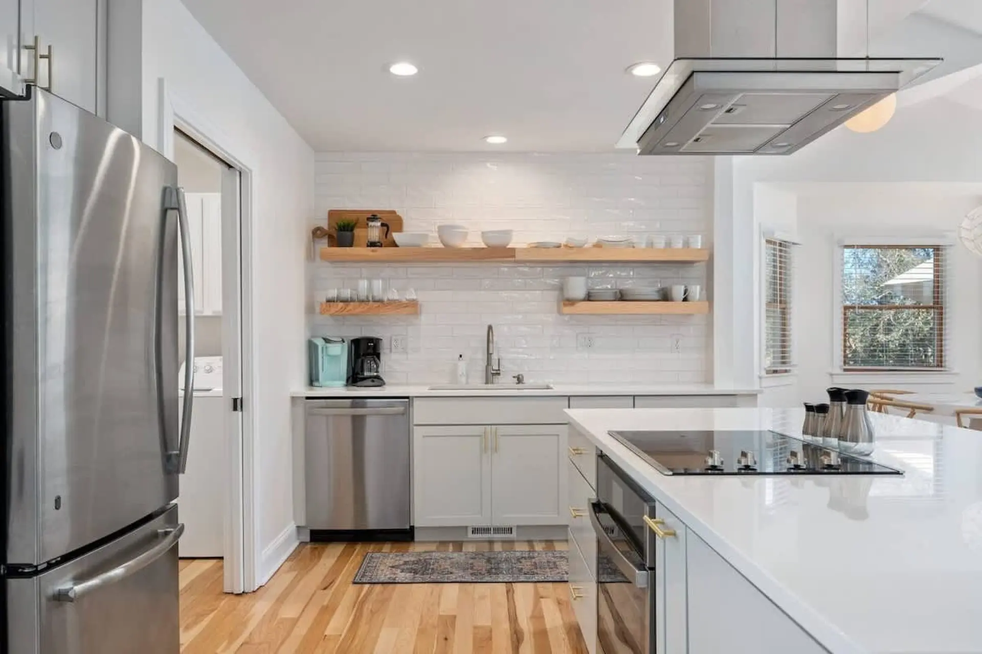 A modern kitchen with stainless steel appliances, subway tile backsplash, and wooden shelves.