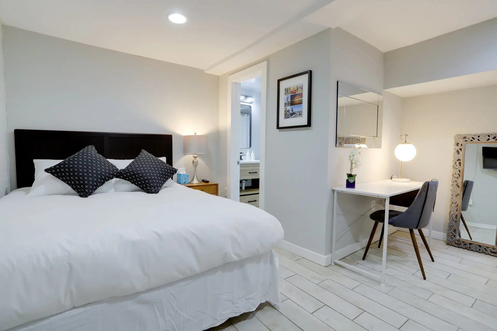 A bedroom with a bed, desk, chair, and a mirror.