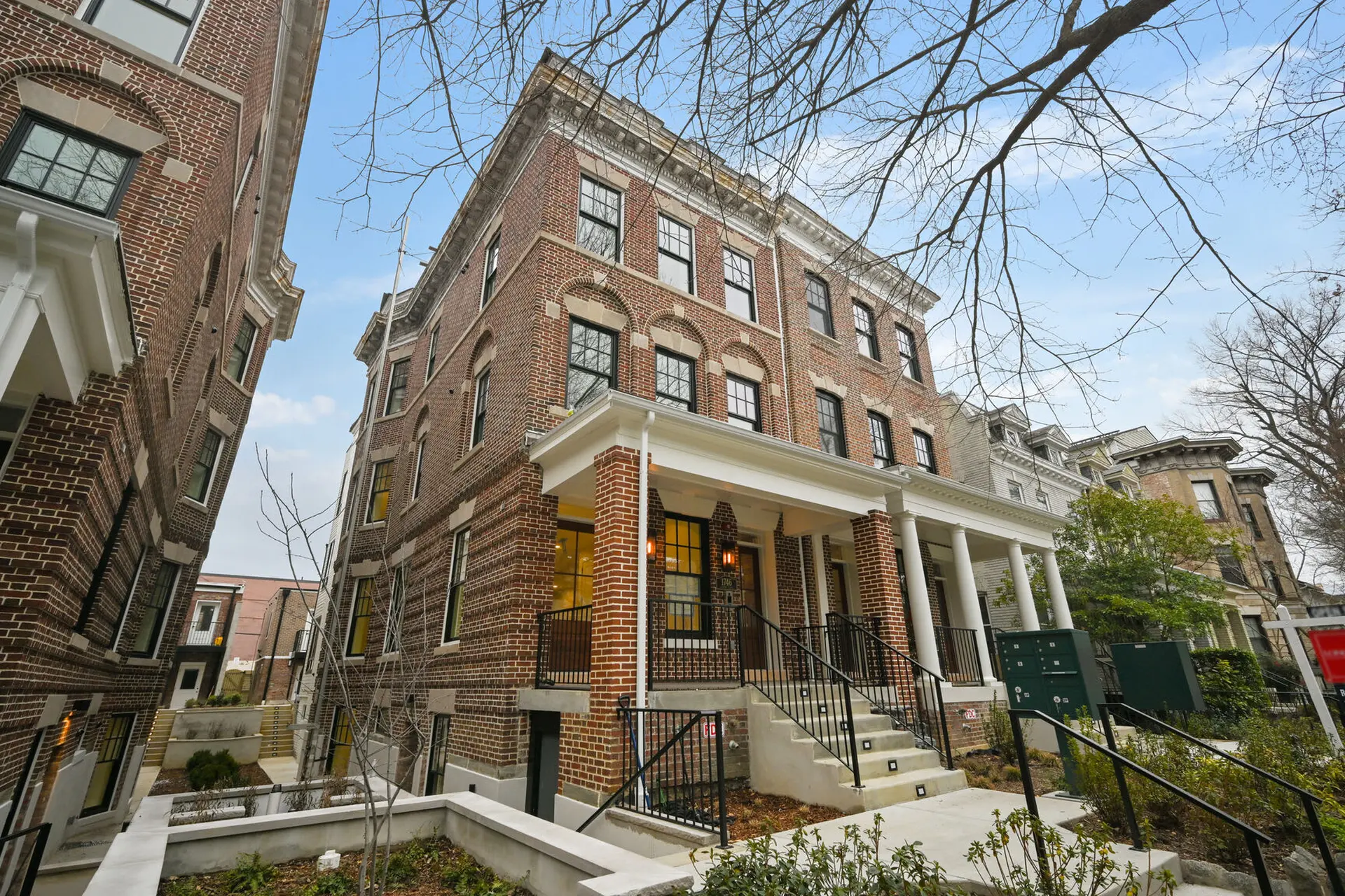 A low-angle shot of a brick building with white trim and a covered porch.