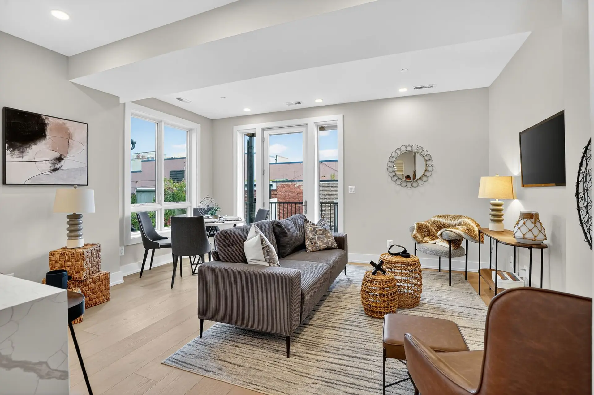 A modern living room with a gray sofa, dining table, and a TV.