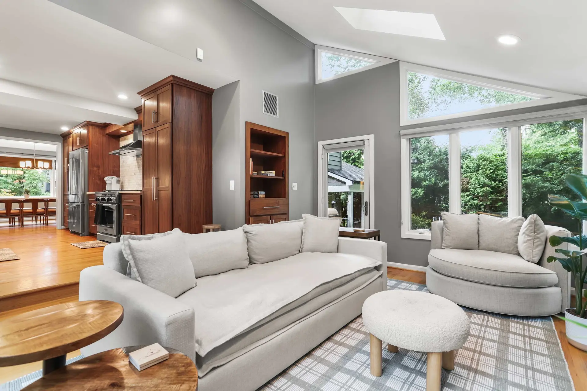 A modern living room with a gray sofa, armchair, and plaid rug.