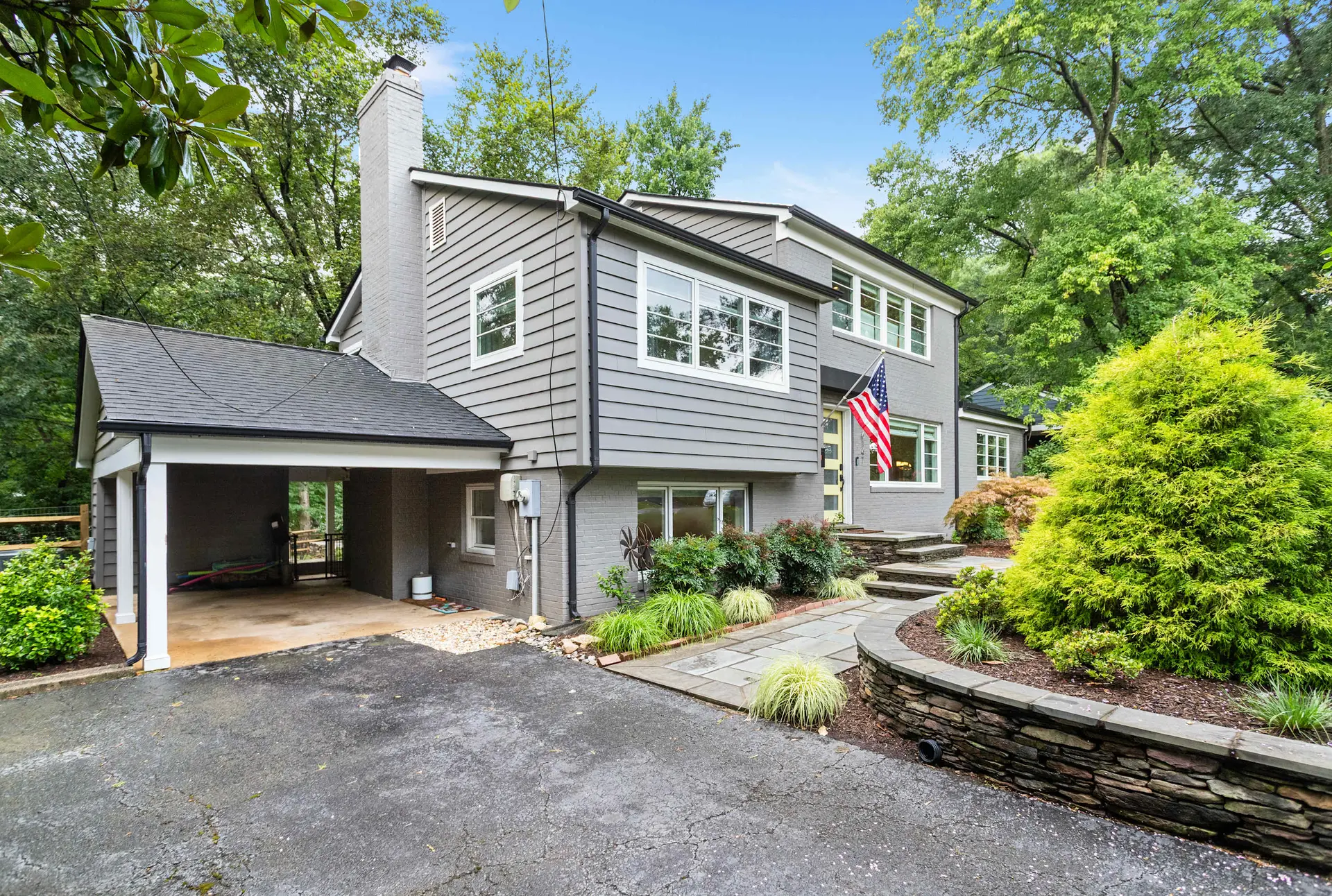 A grey house with a white trim, an attached garage, and a stone walkway.