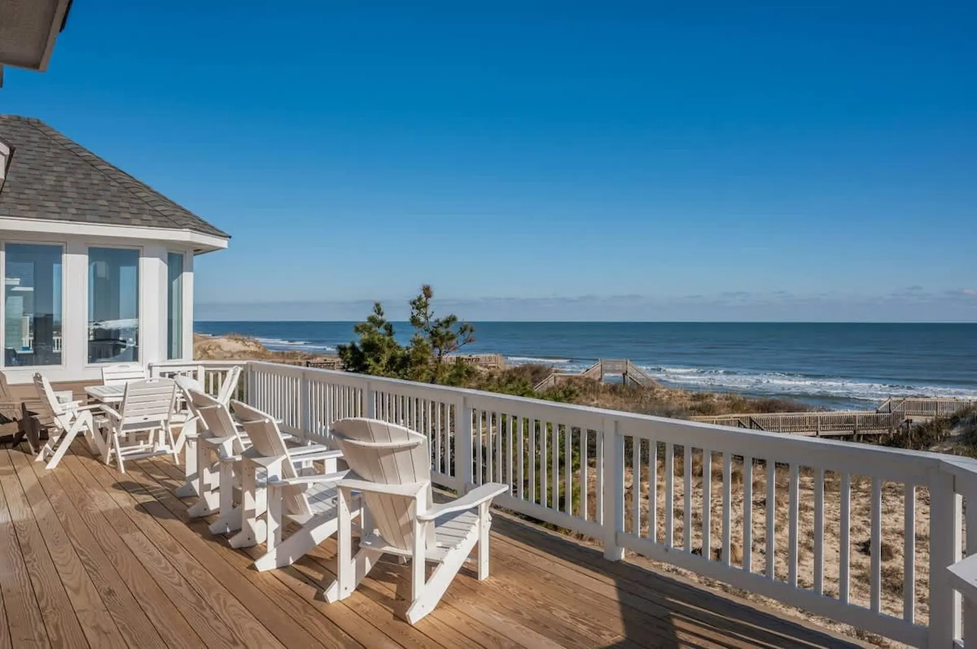 Deck with Adirondack chairs overlooking the ocean and beach.