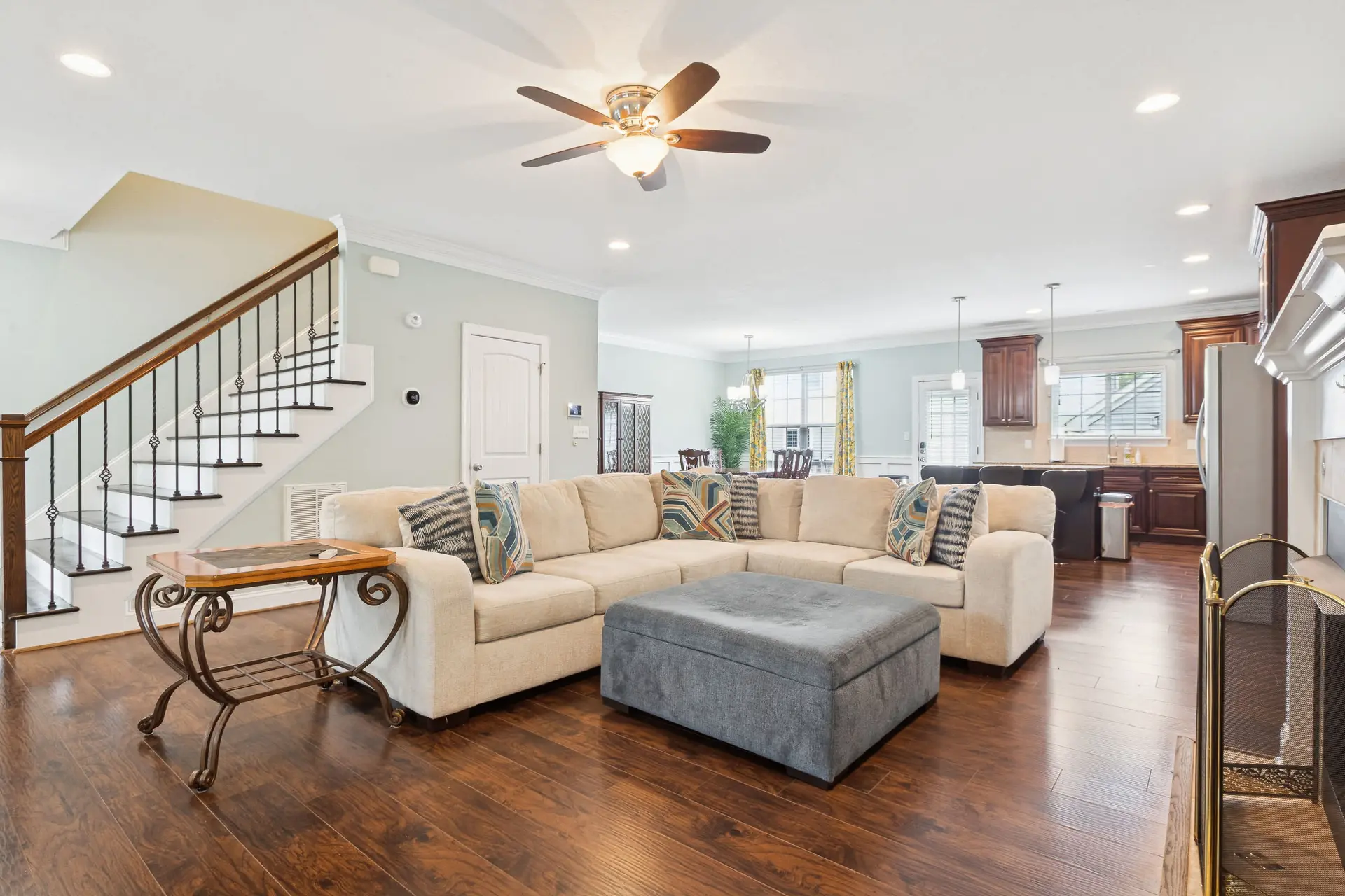 Living room with beige sectional couch, ottoman, and a fireplace screen.