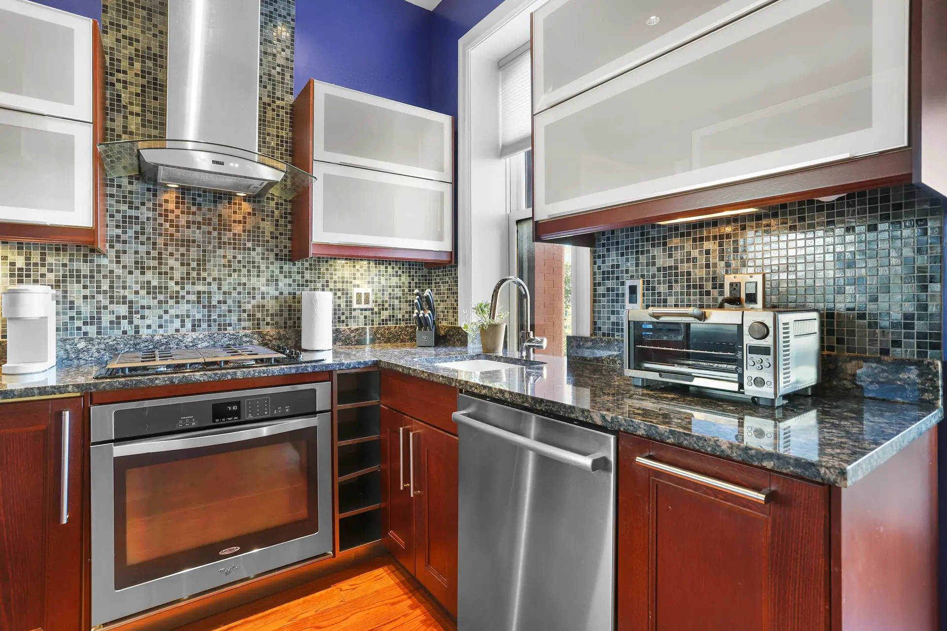 Modern kitchen with dark wood cabinets, granite countertops, and stainless steel appliances.