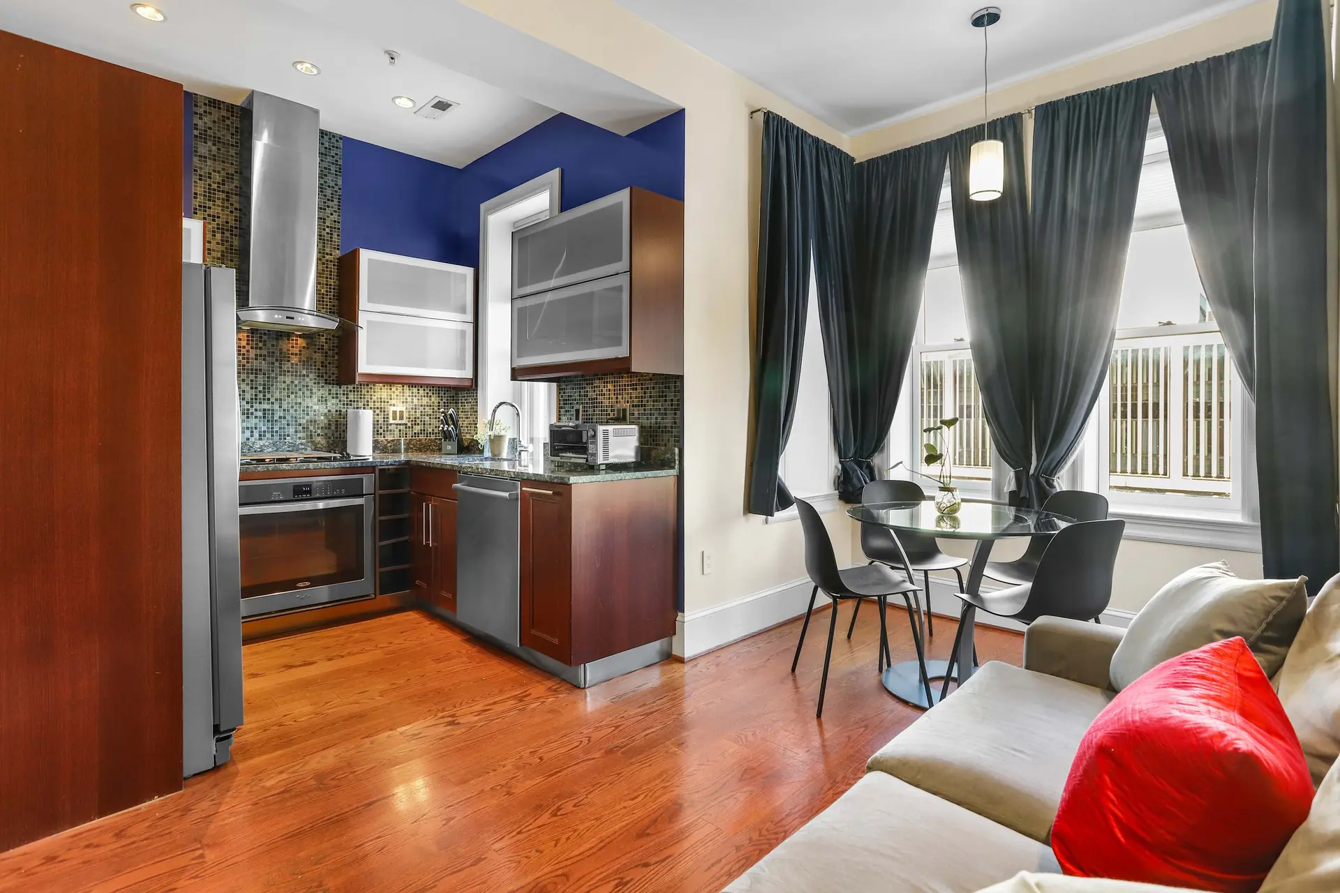 Kitchen and dining area with a sofa, table, chairs, and kitchen appliances.