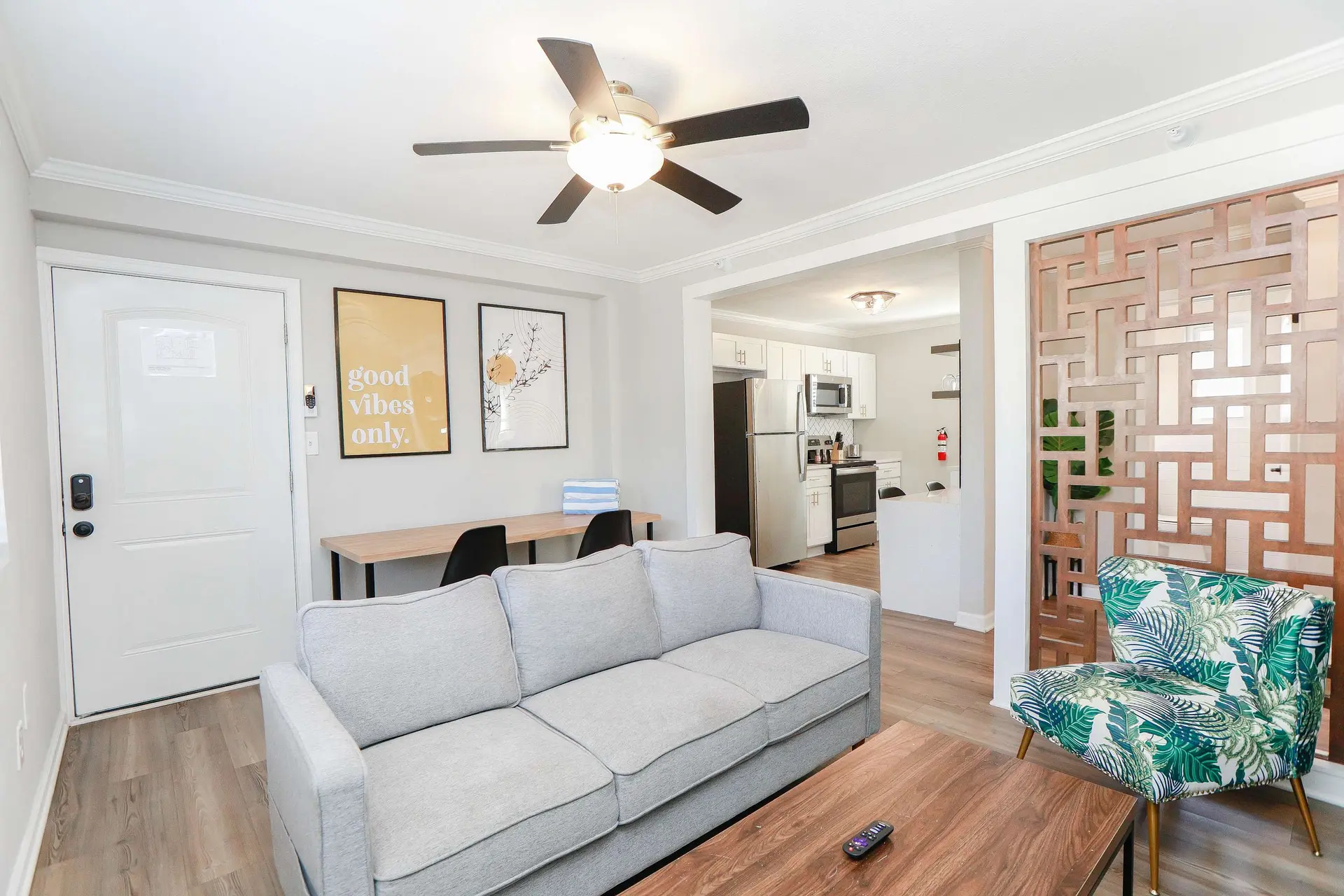 A living room with a grey sofa, a tropical print accent chair, and a coffee table.