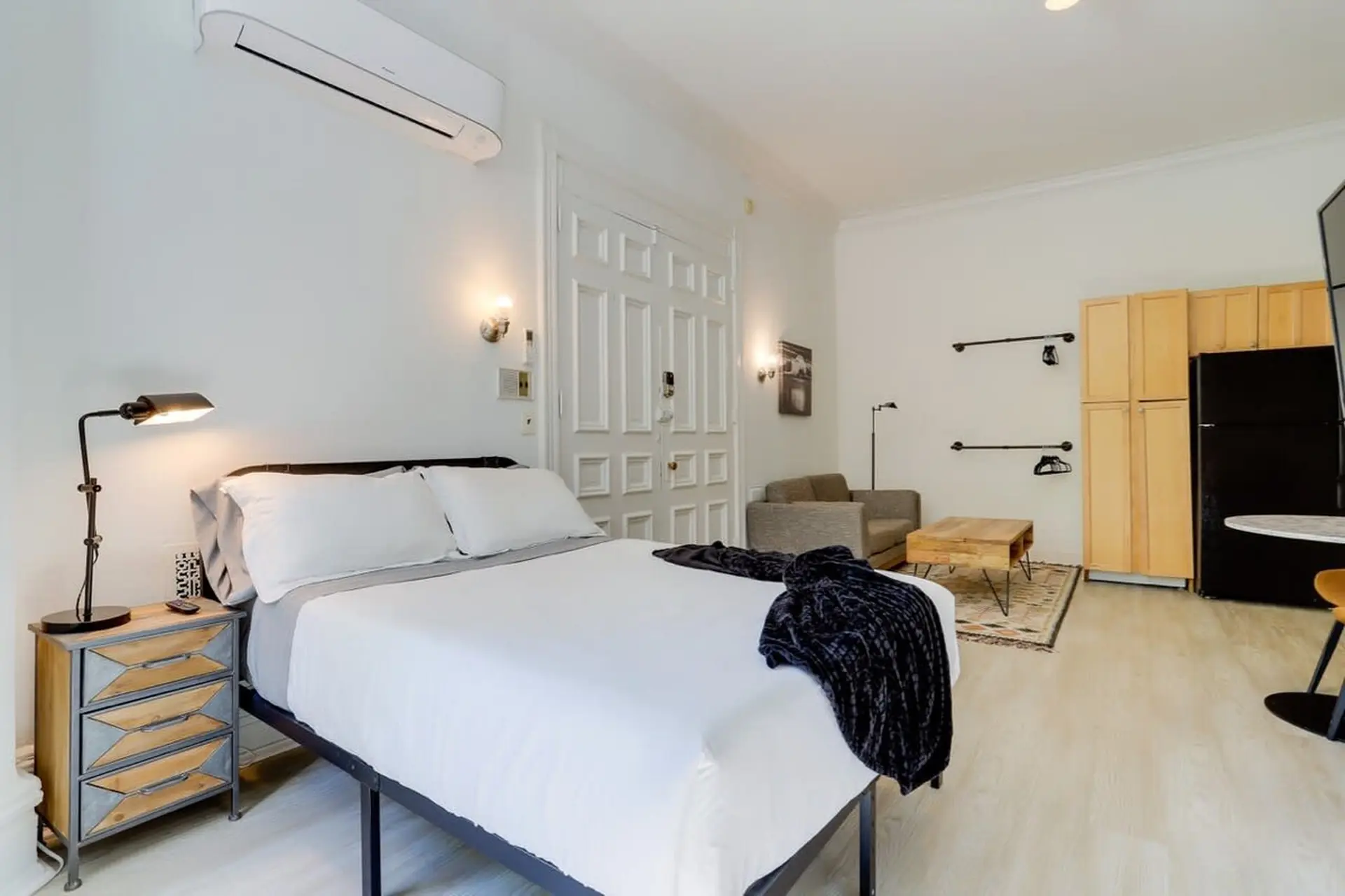 A stylish studio apartment with a bed, couch, and kitchen.