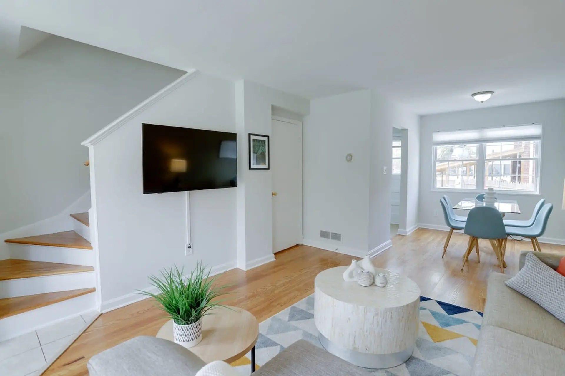 Modern living room with a TV, coffee table, and dining set.