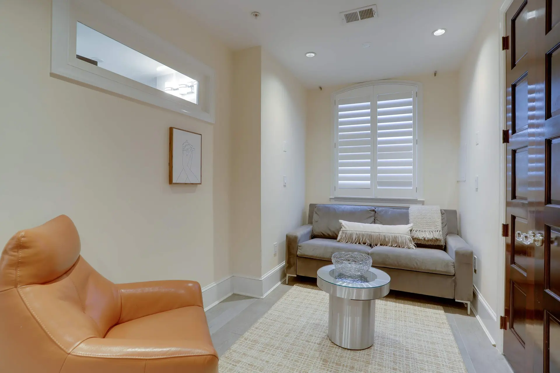 Living room with tan leather armchair, grey sofa, and decorative elements.