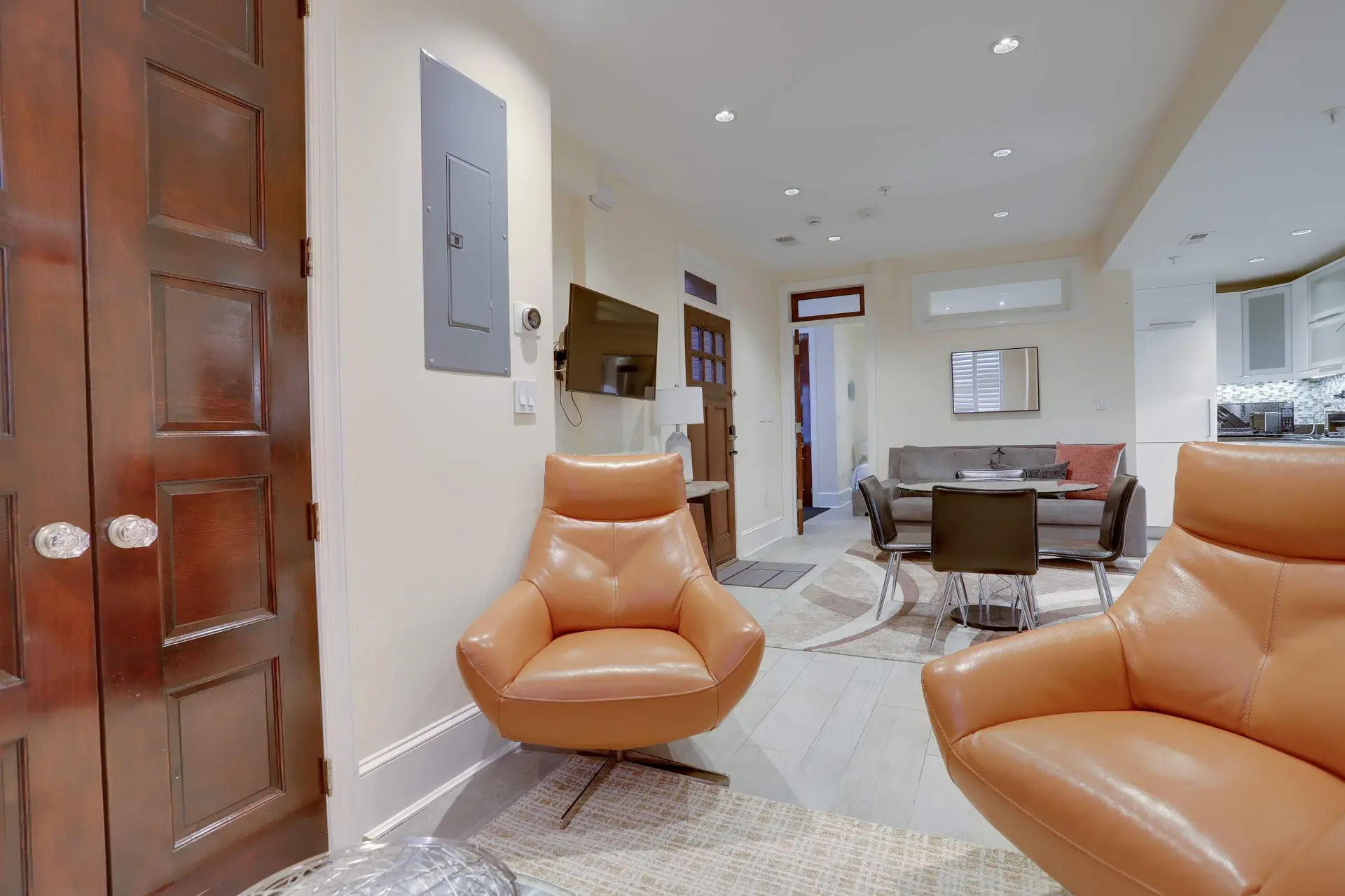 Living room with two orange leather armchairs and a dining table with chairs.
