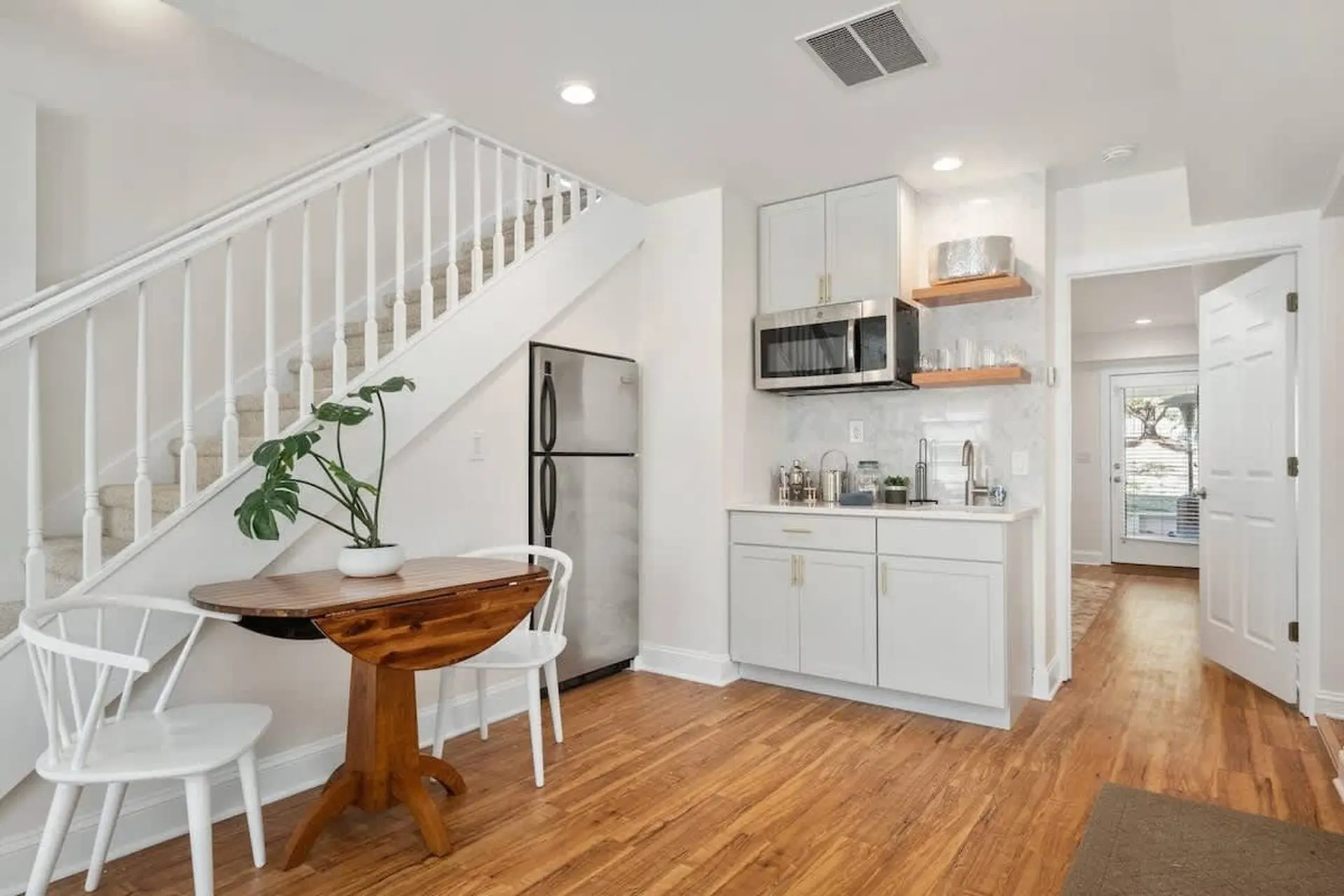 A small kitchen and dining area with white cabinets, a refrigerator, and a table with chairs.