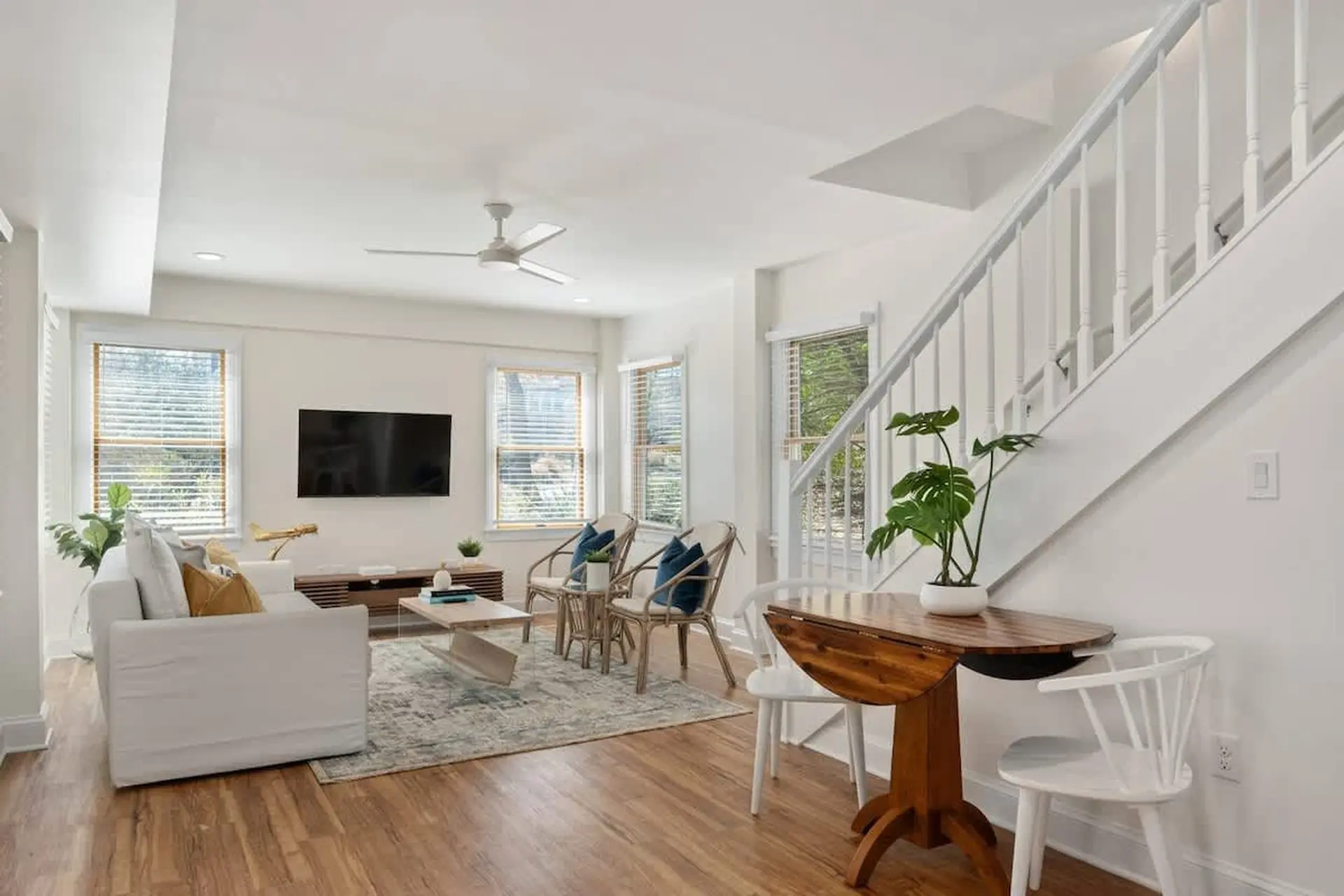 Living room with white sofa, coffee table, tv, and dining nook with a wooden table and chairs.