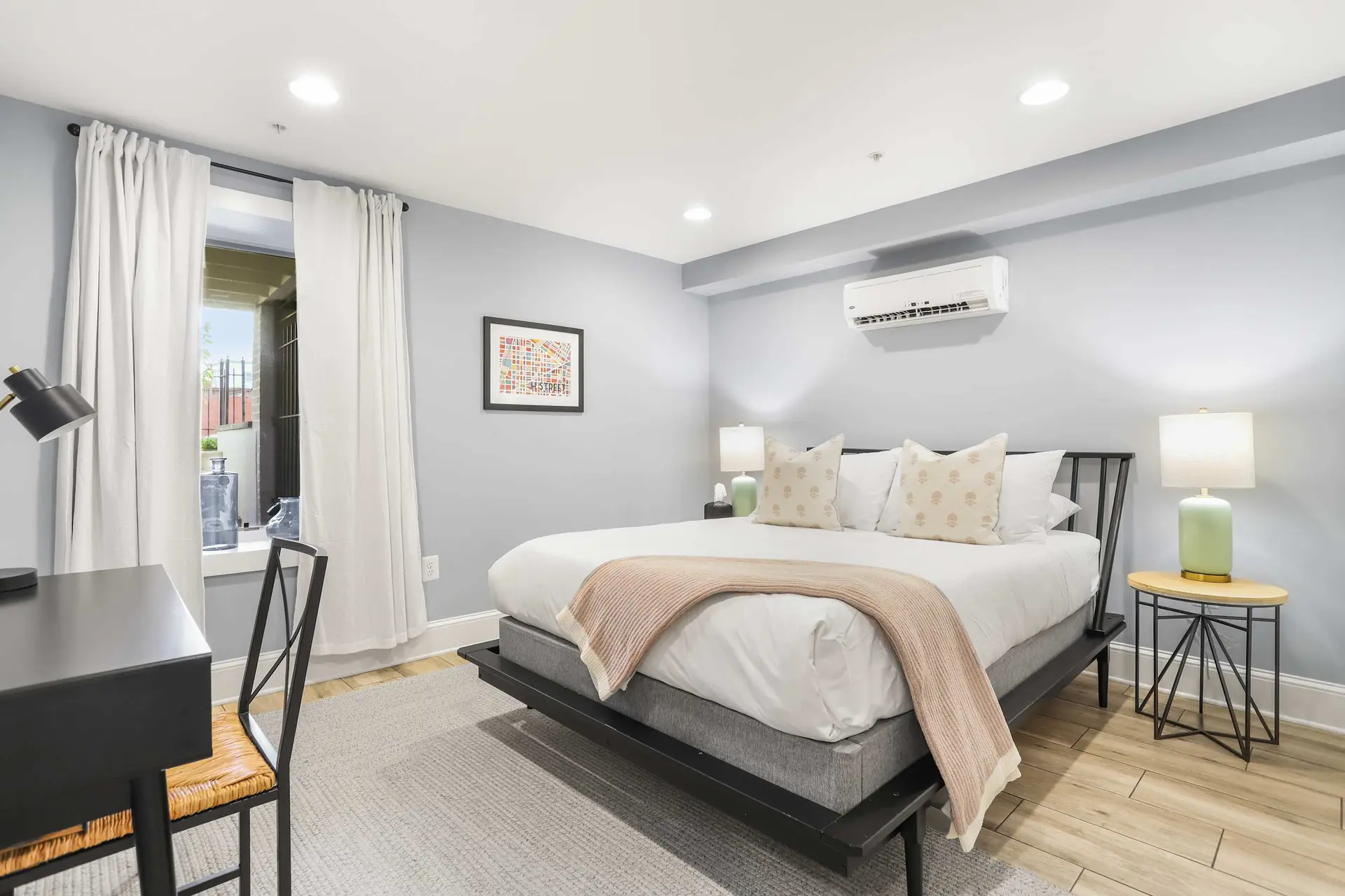 A light gray bedroom with a bed, desk, and window.
