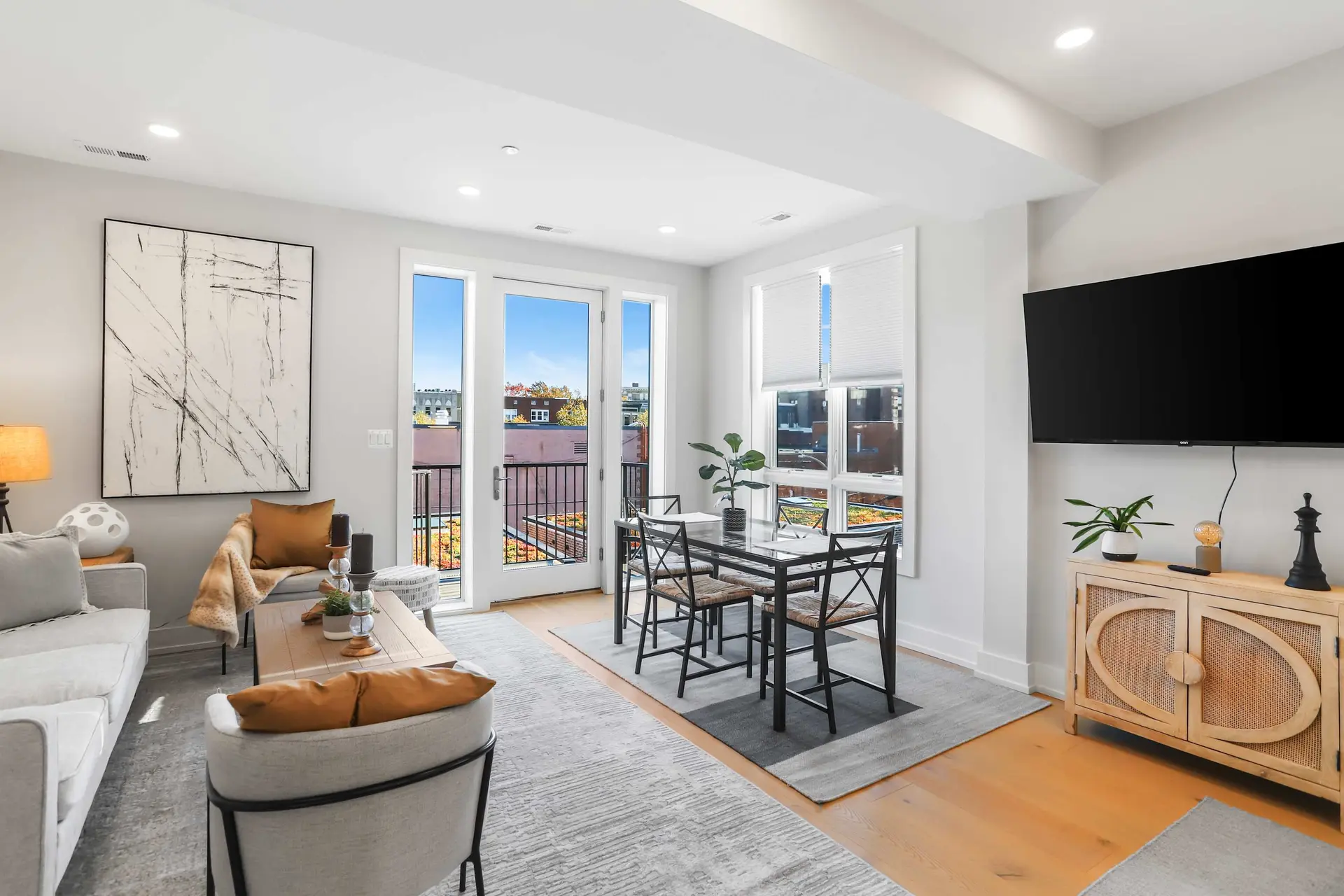 Modern living and dining room with a gray sofa, dining table, and TV.