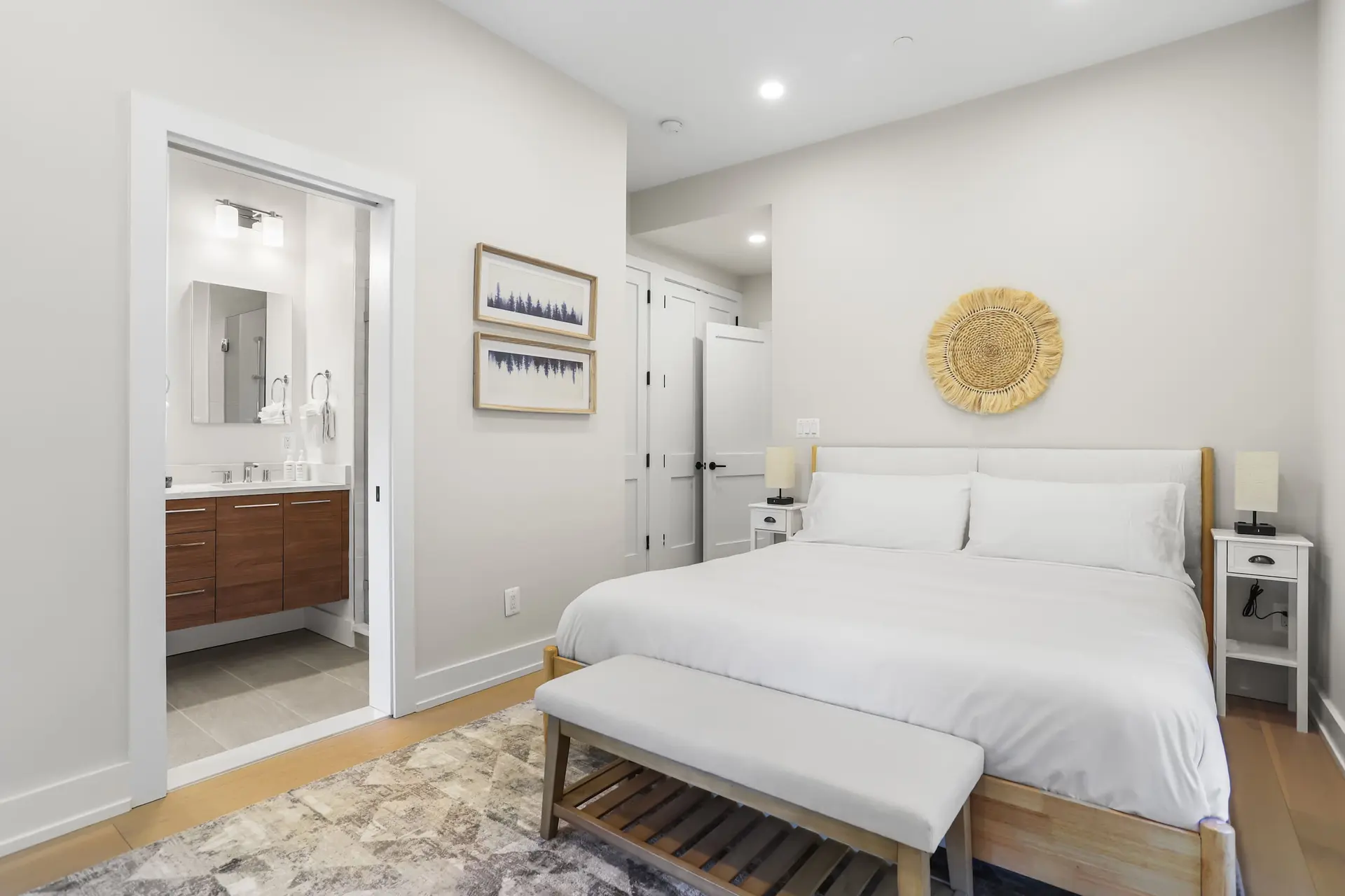 Bedroom with a bed, ensuite bathroom, and two framed art pieces.