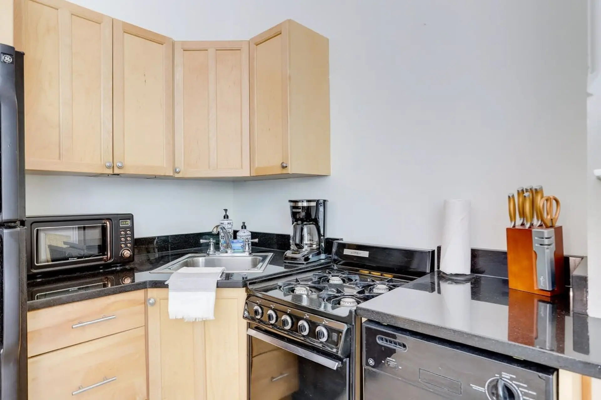 A small kitchen with wood cabinets, black appliances, and granite countertops.