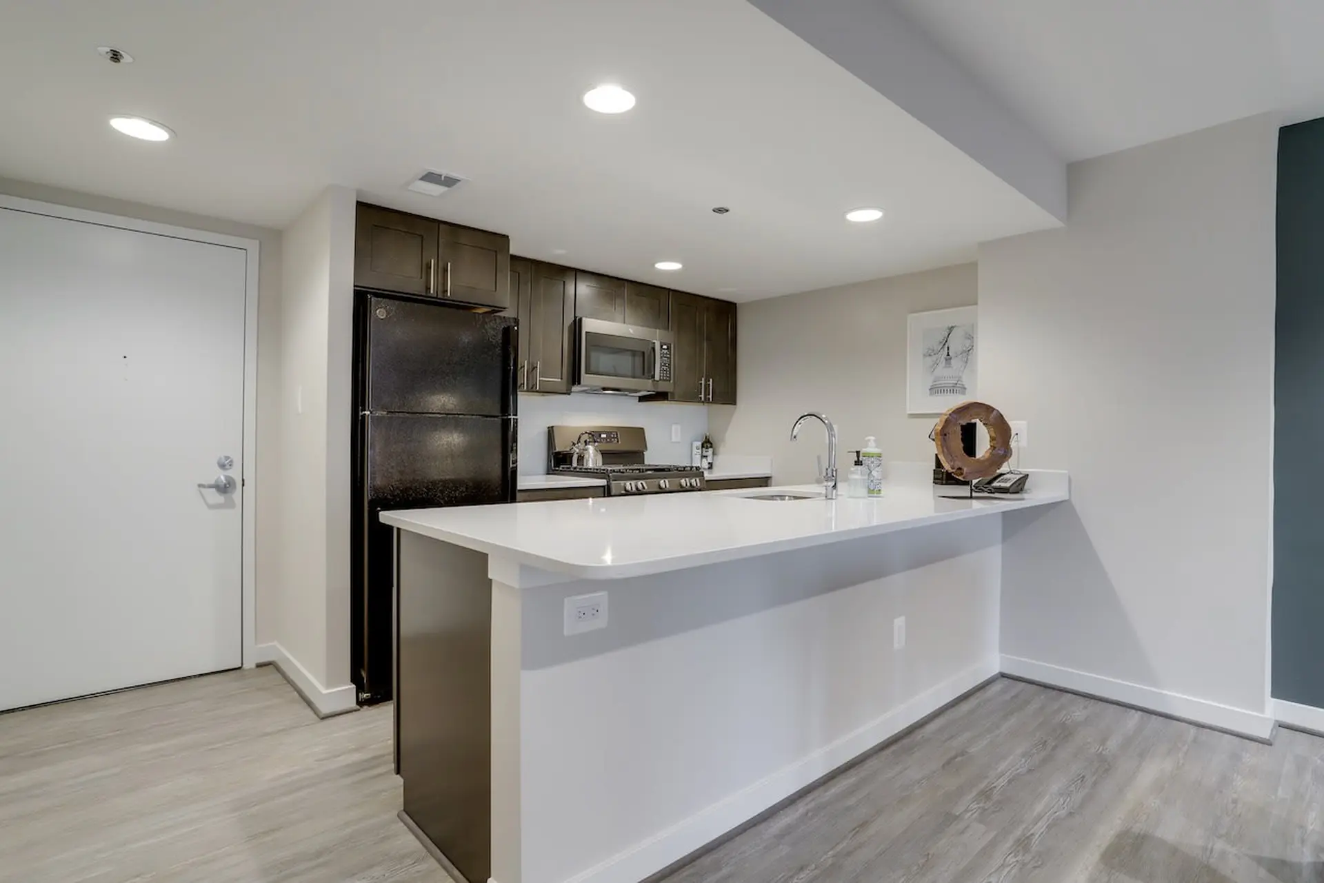 Kitchen with white island, dark cabinets, and black refrigerator.