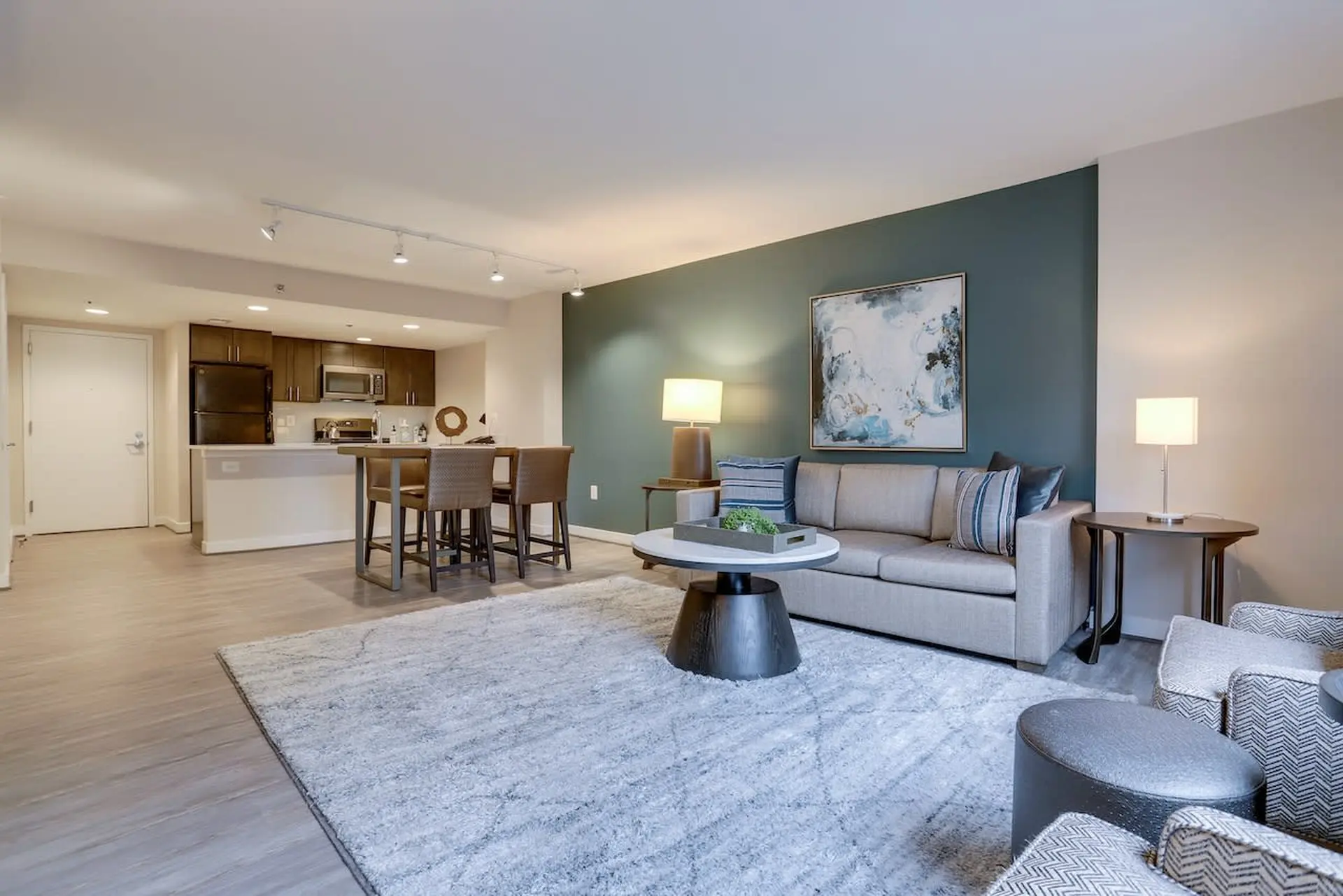 A modern living room and kitchen area with a sofa, coffee table, and bar stools.