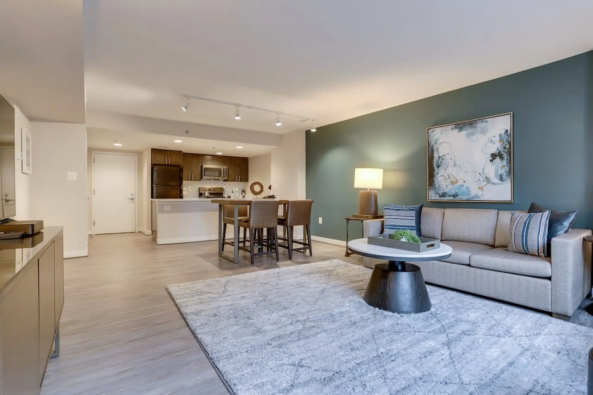 Living room with teal accent wall, sofa, coffee table, and bar seating.