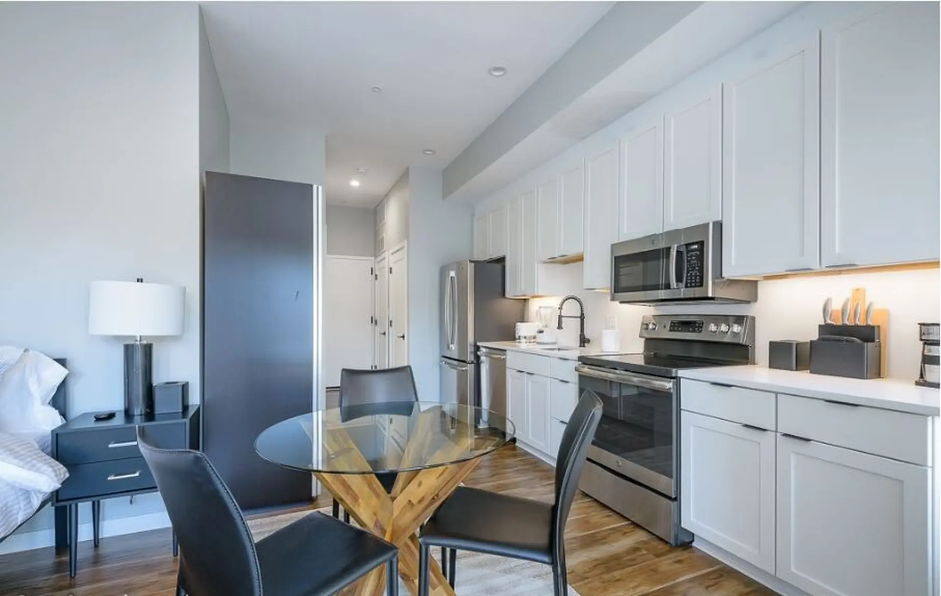 Modern studio apartment kitchen and dining area with stainless steel appliances.