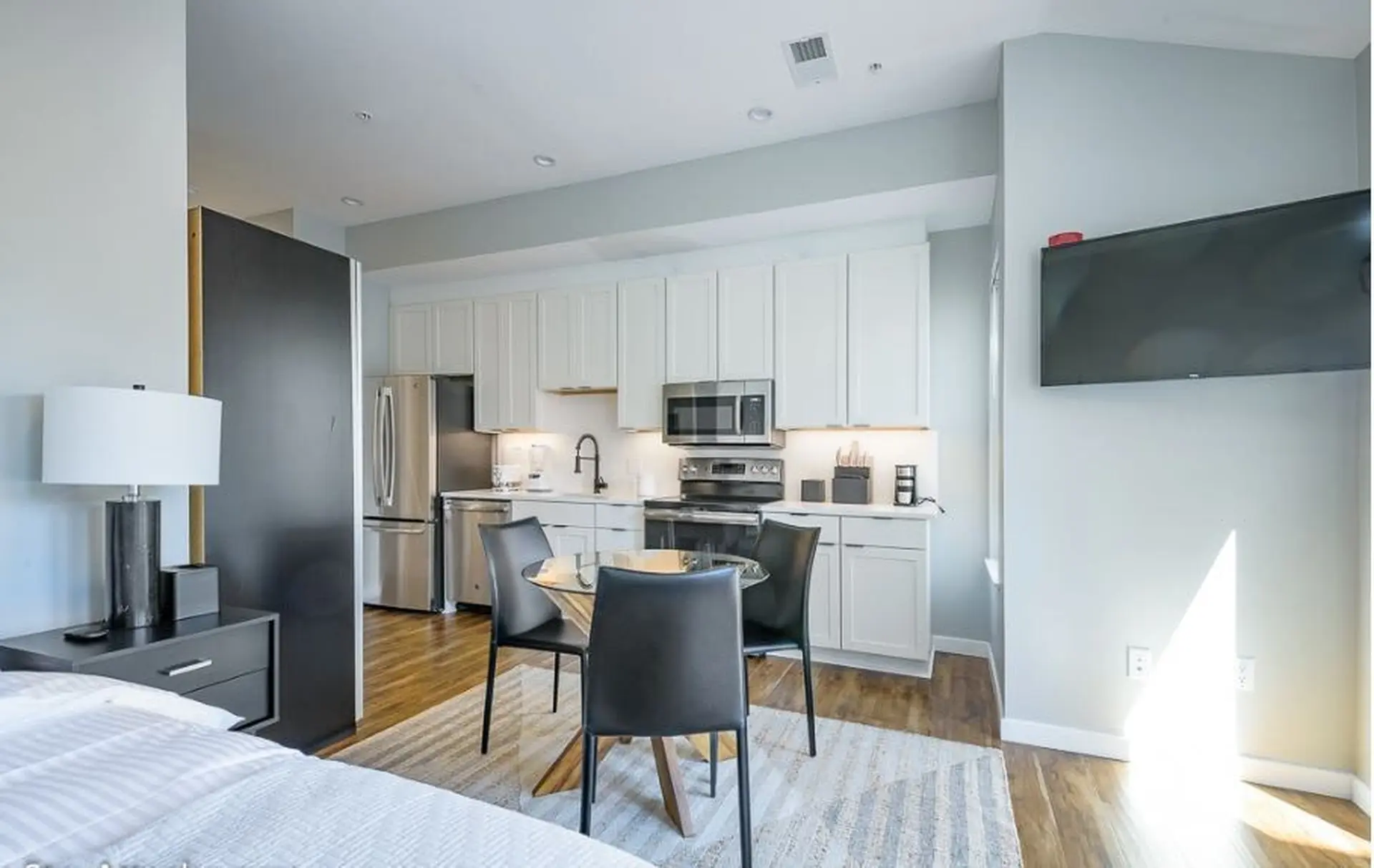 A studio apartment featuring a bed, kitchen, dining area, and TV.