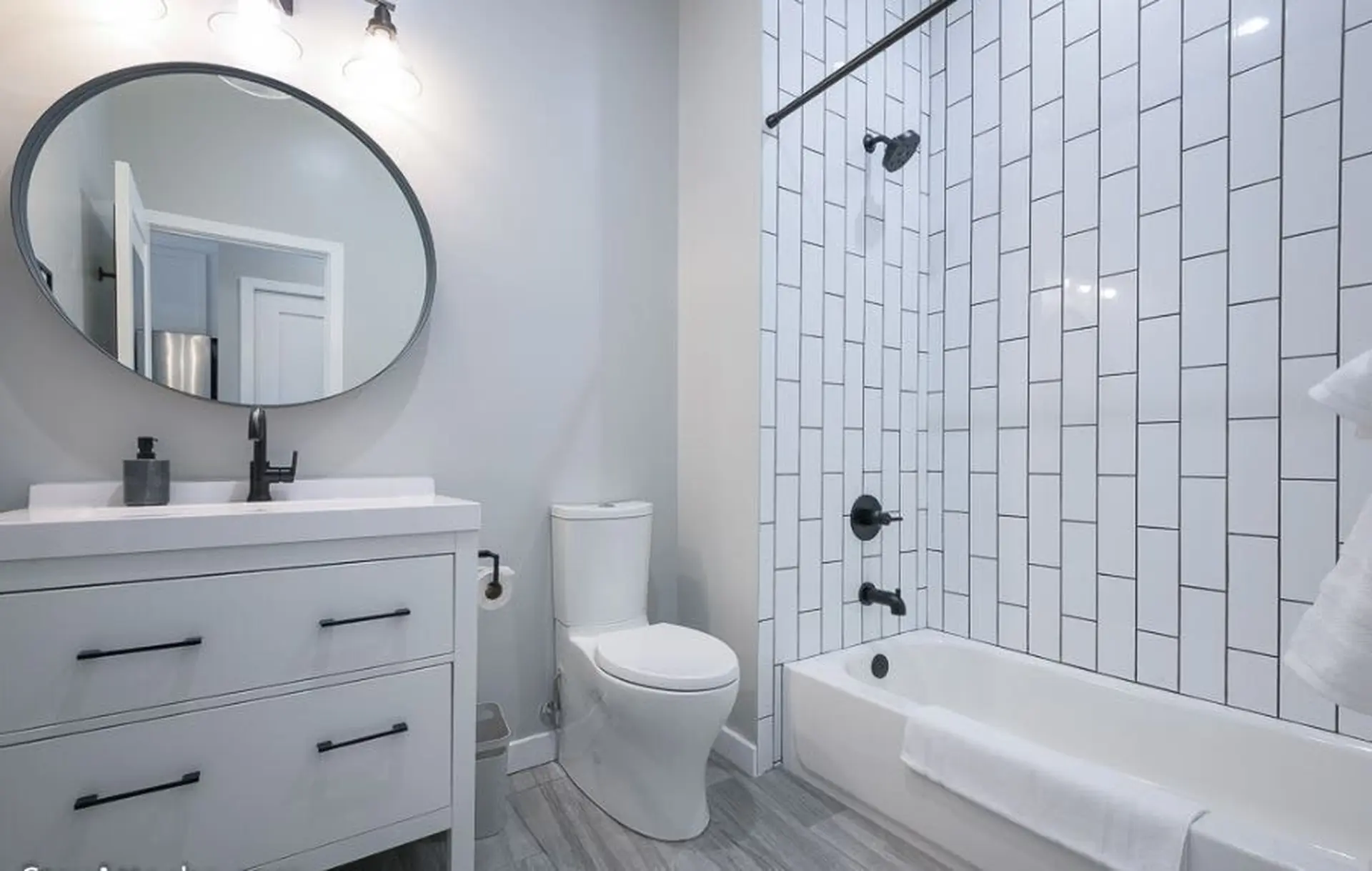 Modern bathroom with white subway tile shower, vanity, and toilet.